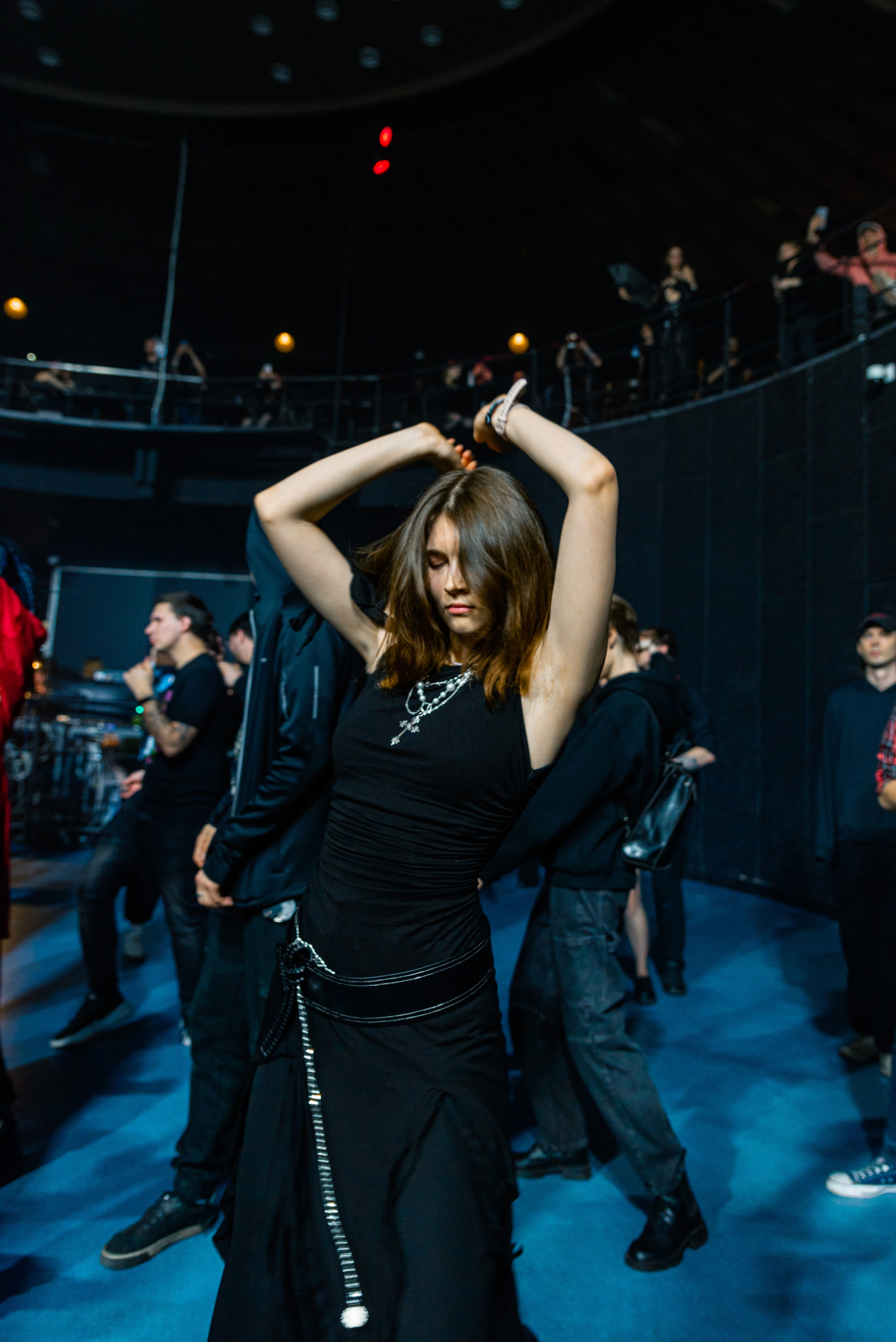 Девушка танцует в концертном зале среди зрителей, поднимает руки над головой