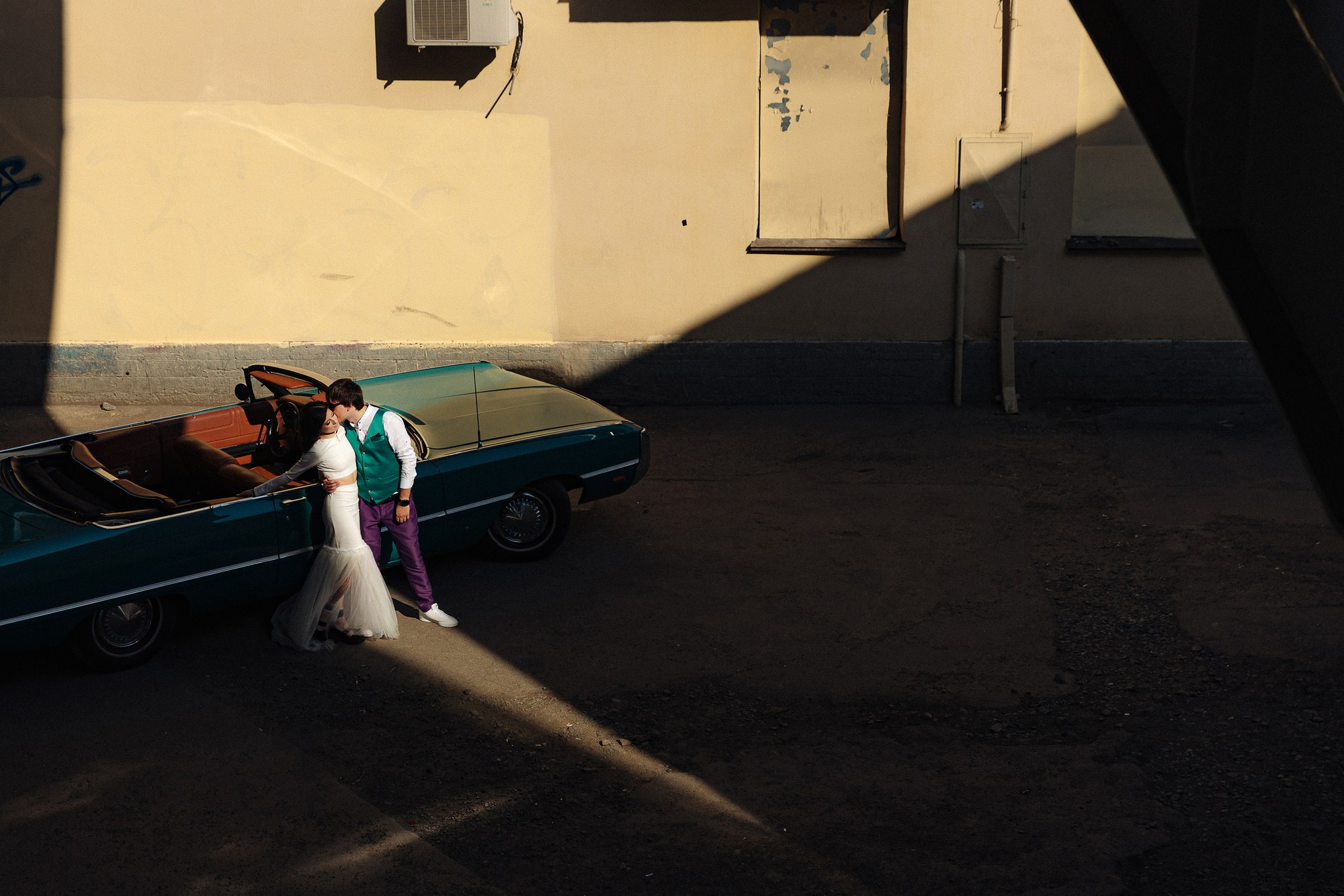 Невеста и жених обнимаются возле машины под мостом Бетанкура в СПб