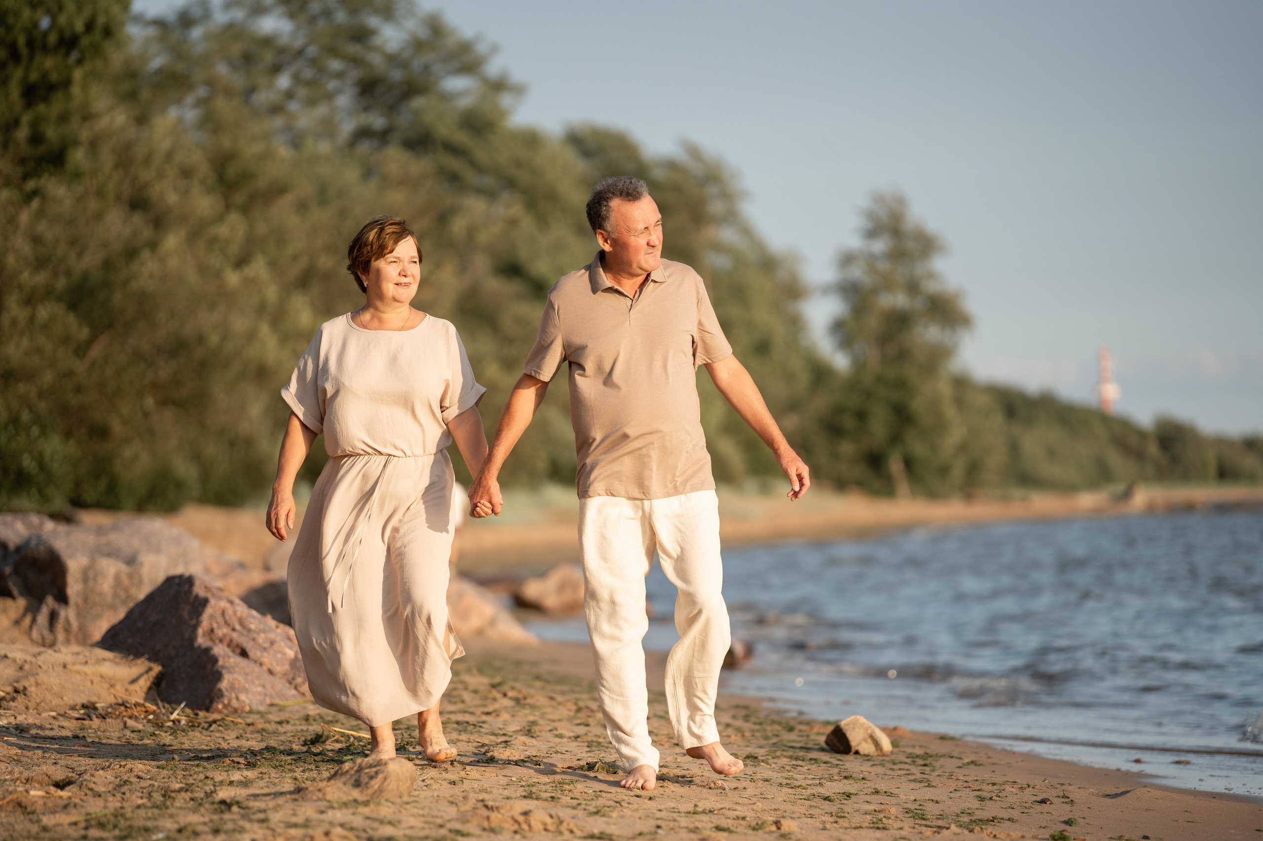 Пожилая пара прогуливаются по берегу моря.