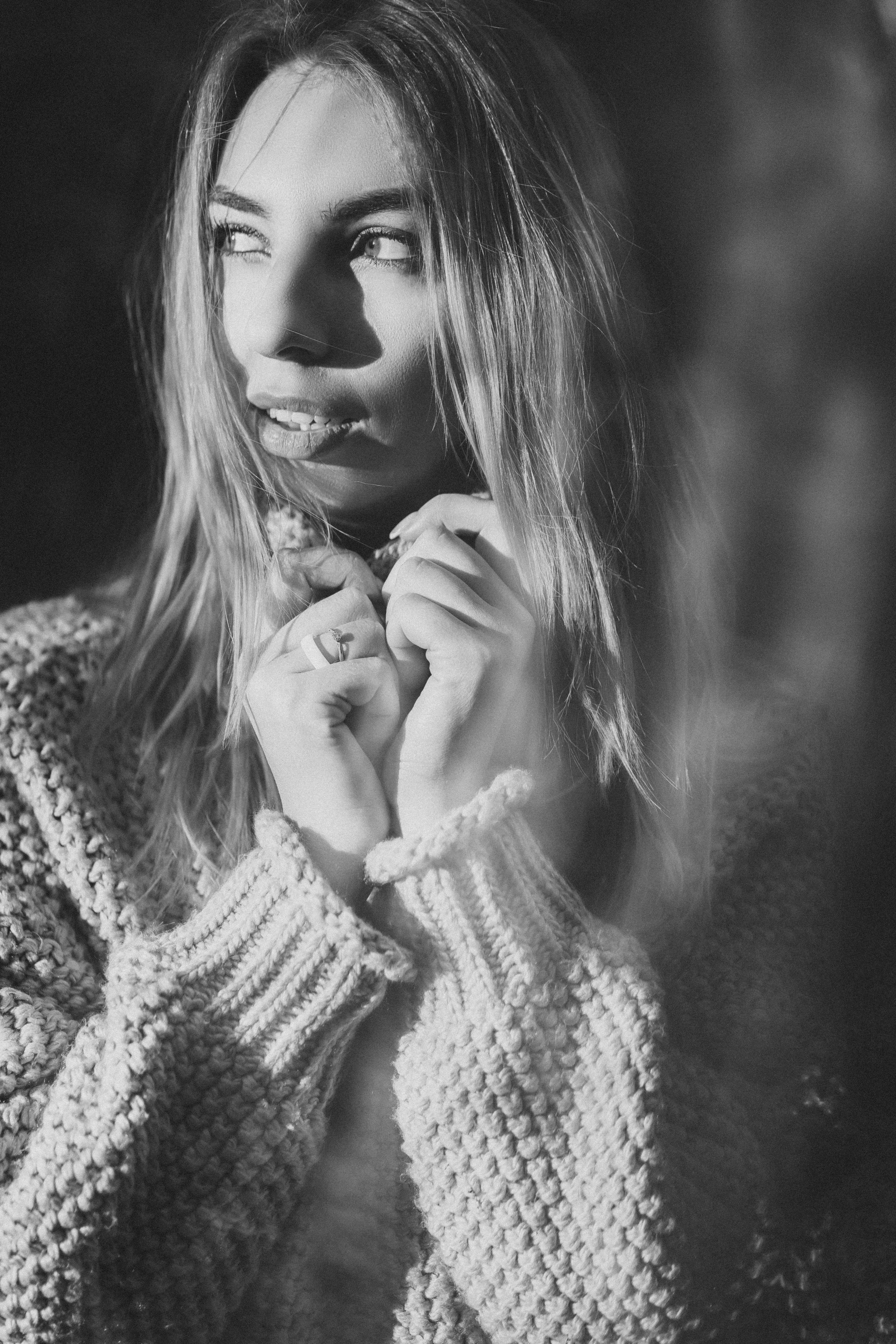 Девушка в вязанном свитере с горлом, уютный портрет при солнечном свете, руки у лица