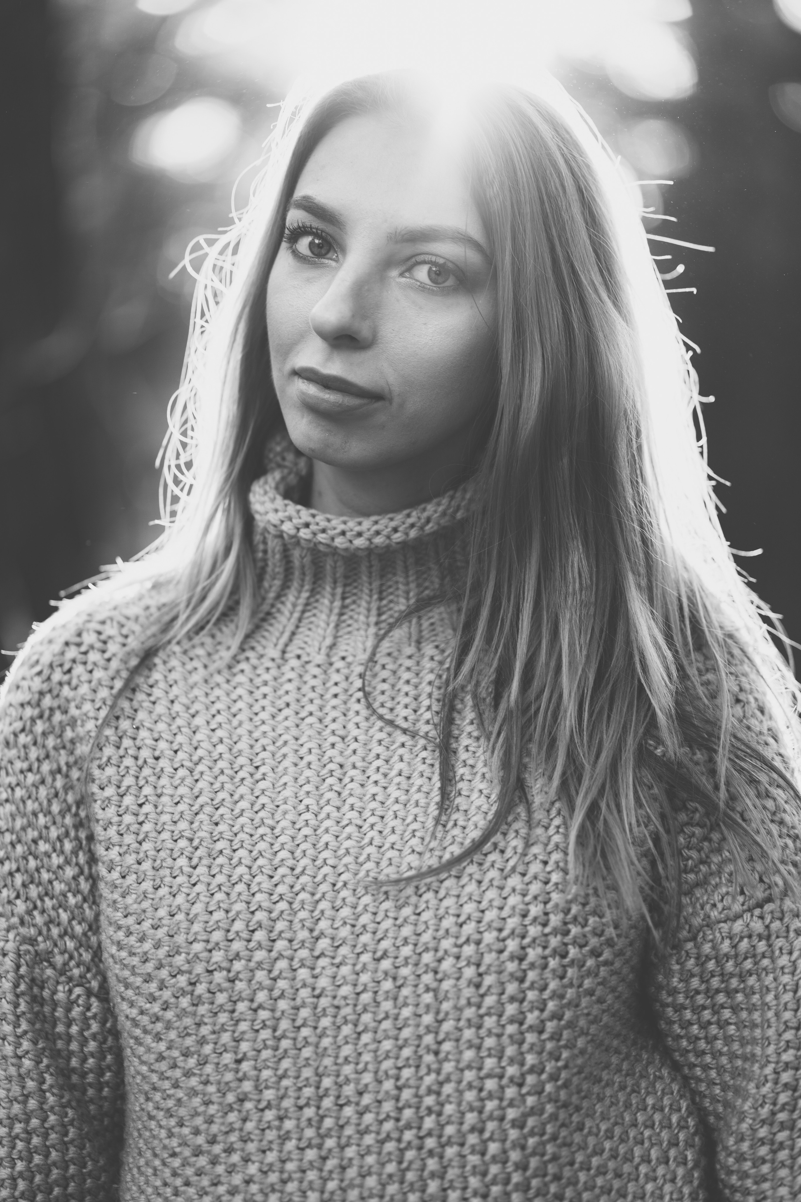 Девушка в вязанном свитере с горлом, мило улыбается и смотрит в камеру