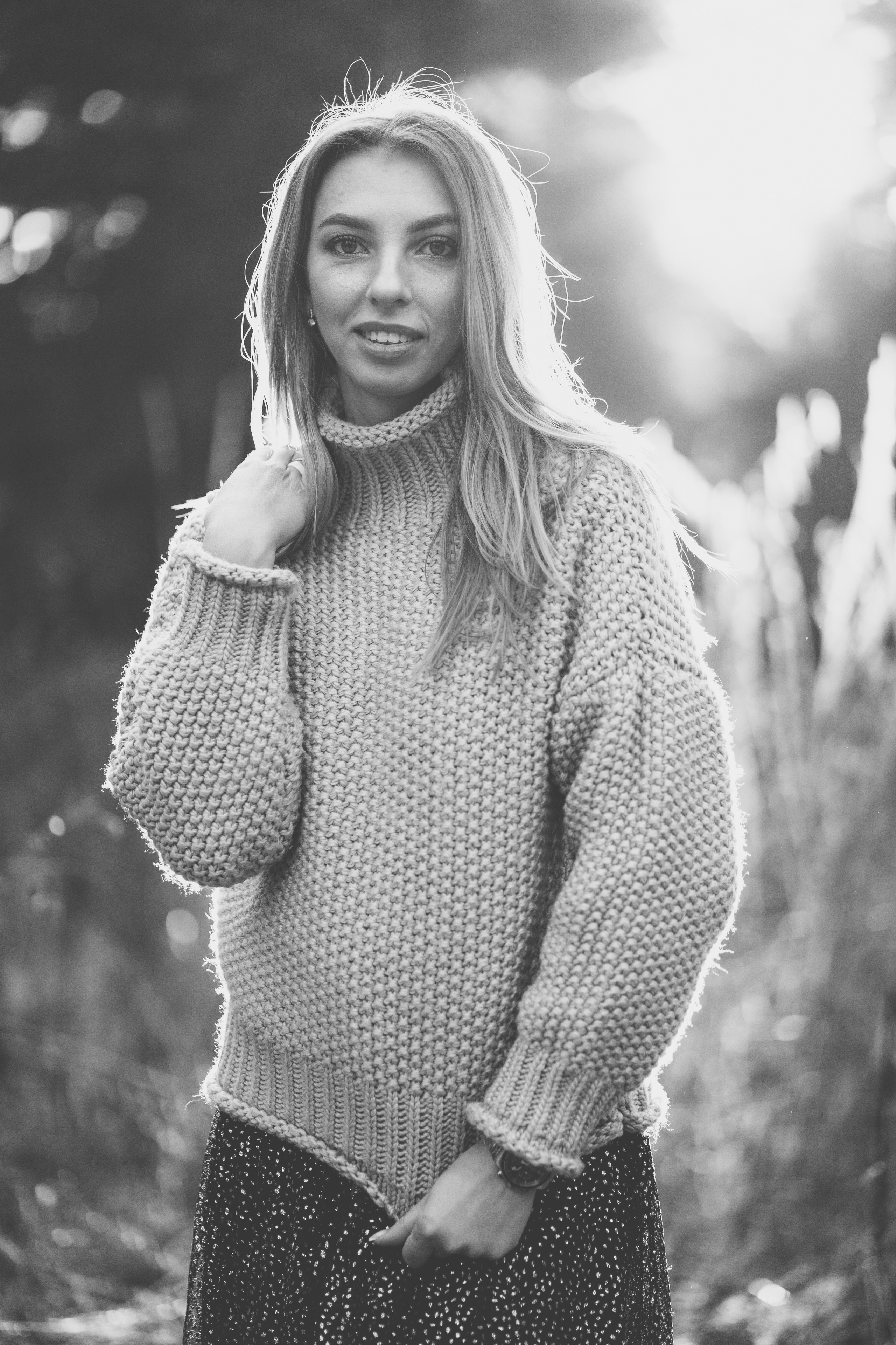 Девушка в вязанном свитере с горлом, мило улыбается и смотрит в камеру