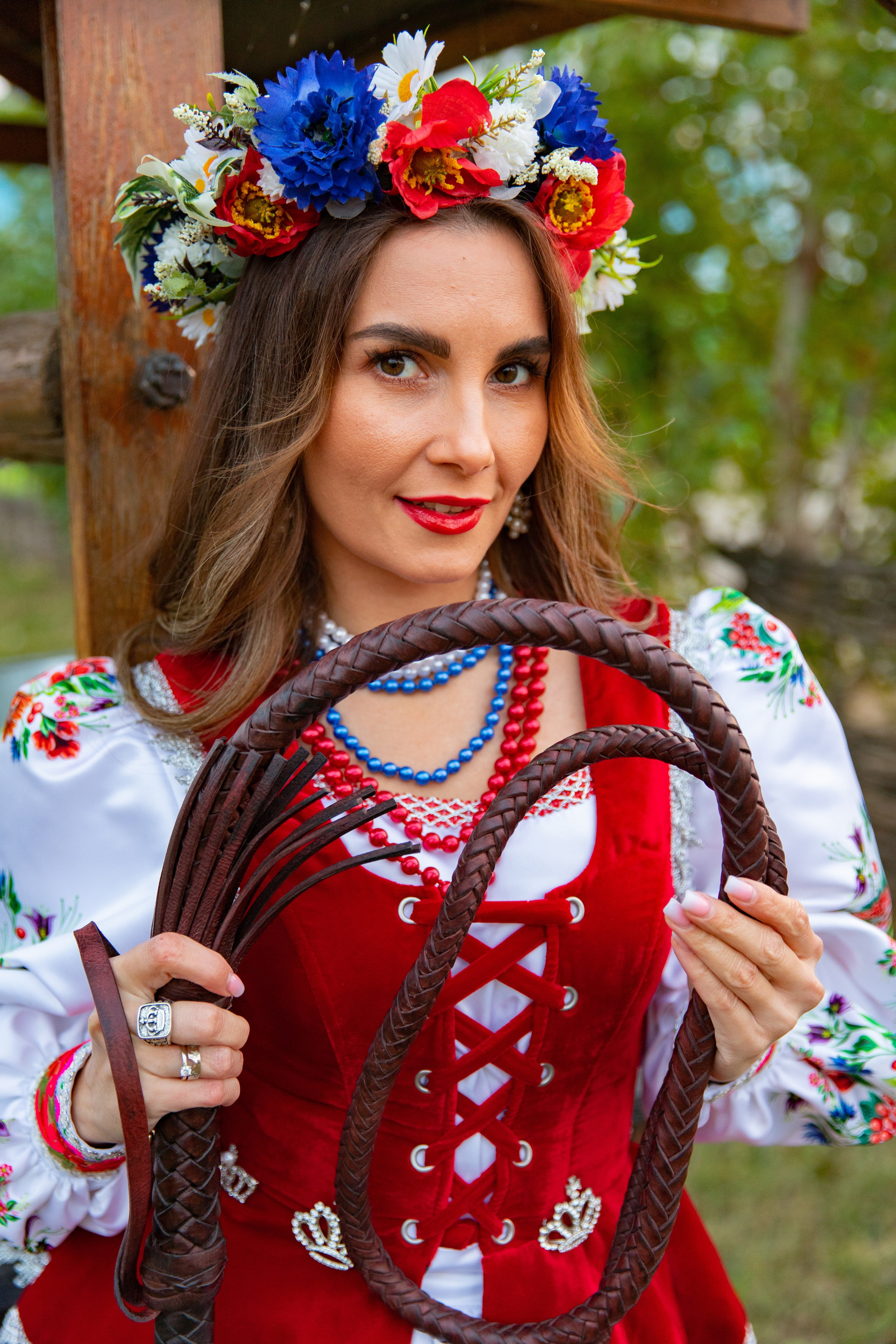 Молодая казачка держит плетку в руках, олицетворяя силу и уверенность, на фоне традиционного уклада жизни.