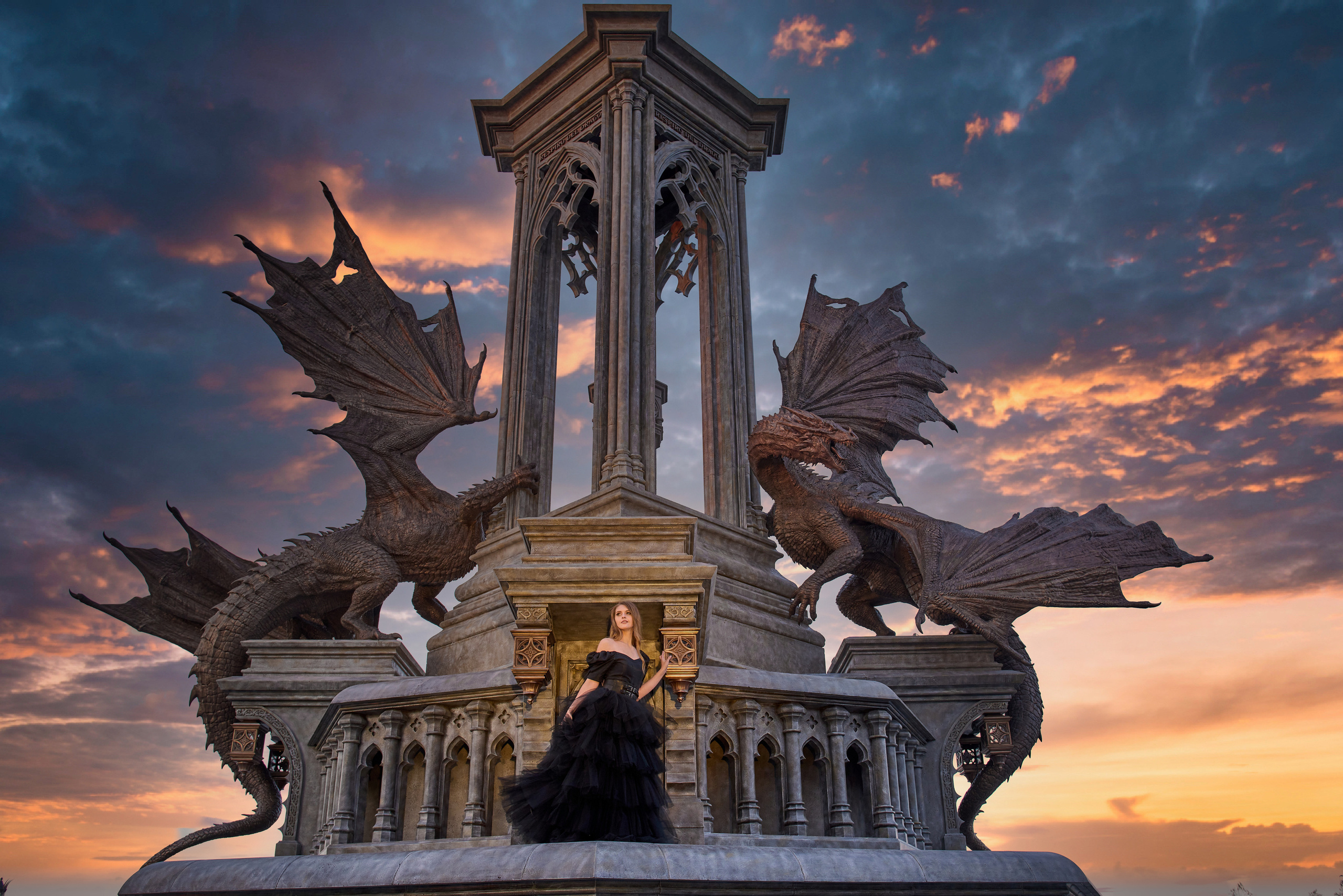 Монументальная композиция с несколькими драконами на вершине колоннады замка Гарибальди, освещённая закатным солнцем.