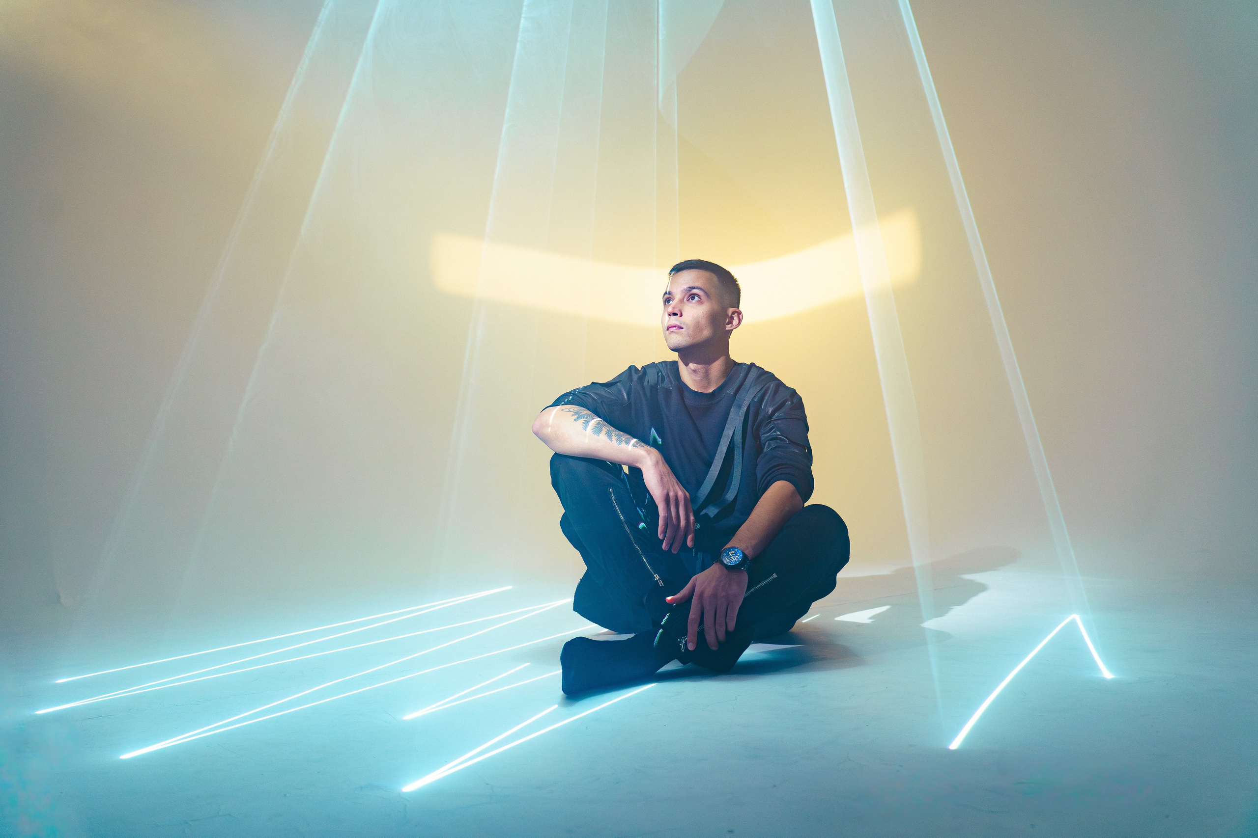 Мужчина сидит на полу среди расходящихся лазерных линий