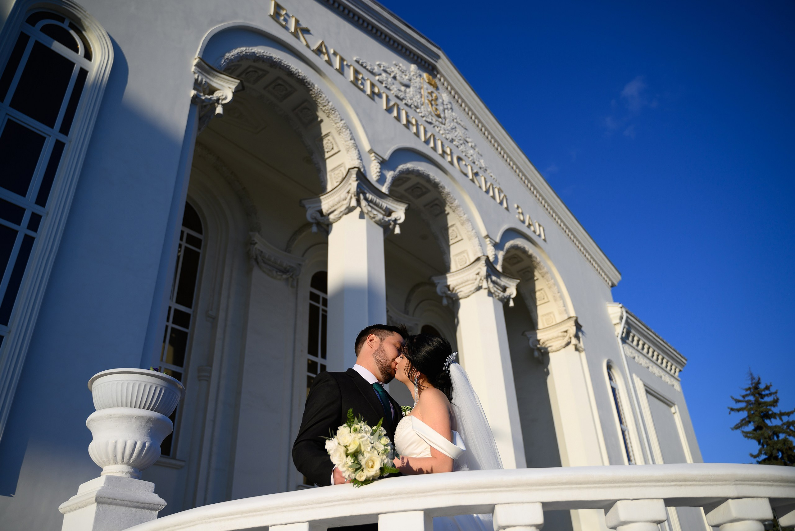 Жених и невеста целуются на фоне Екатерининского дворца бракосочетания.