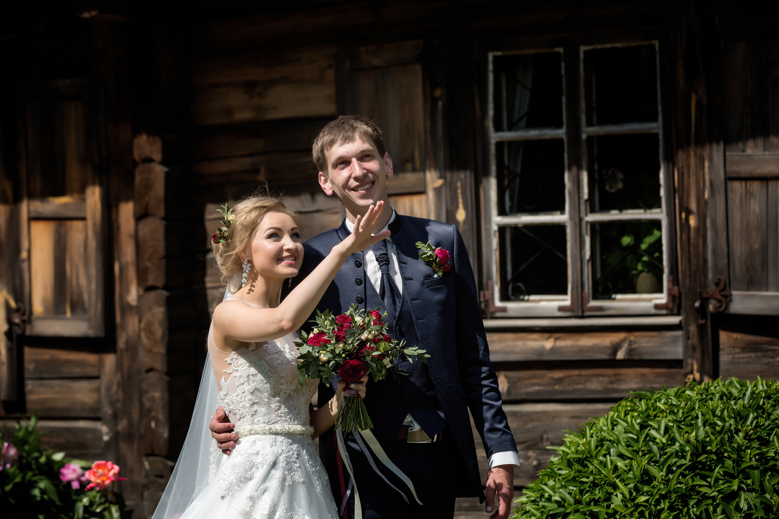 жених с невестой обнимаются на фоне старого деревянного домика