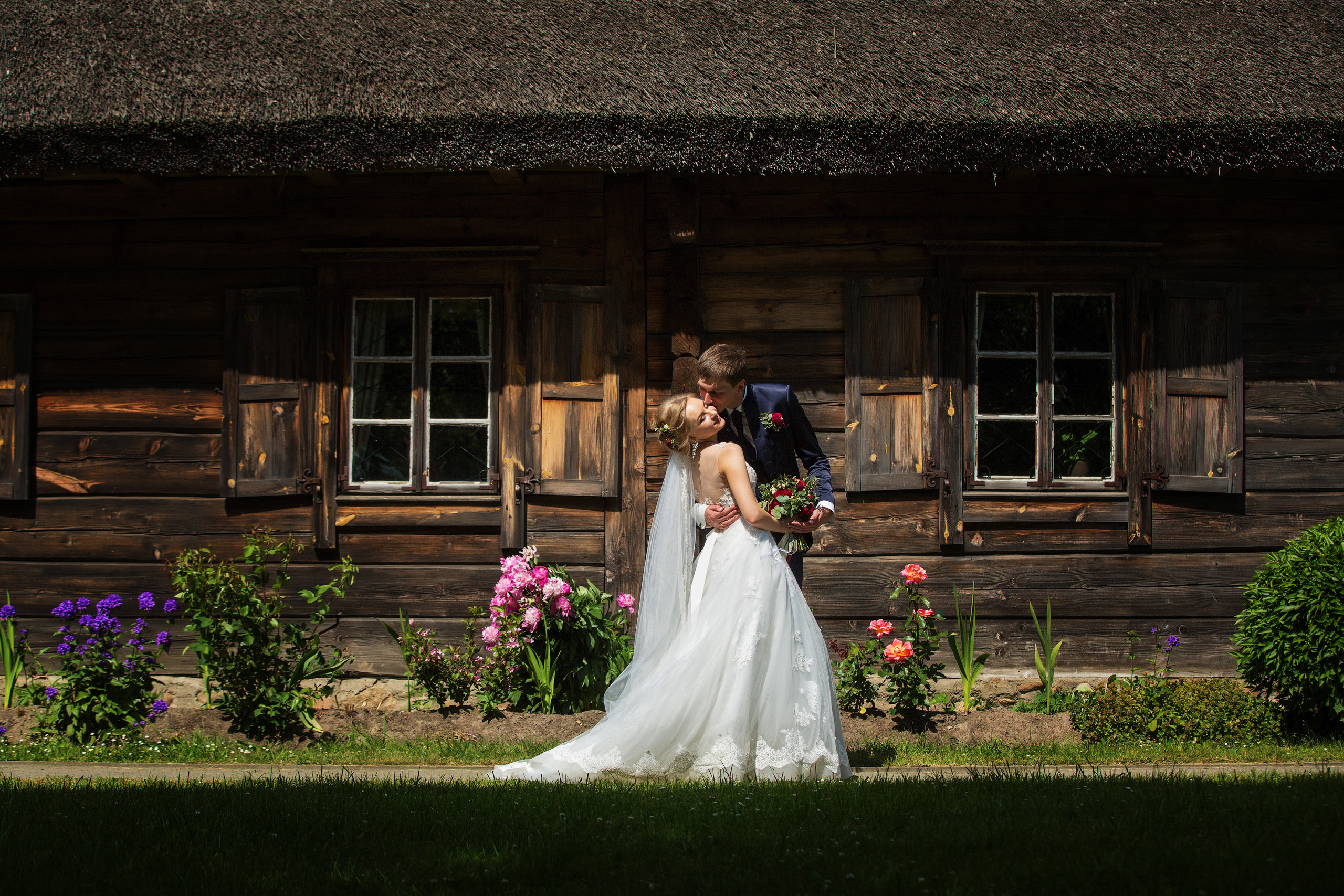 жених с невестой обнимаются на фоне старого деревянного домика