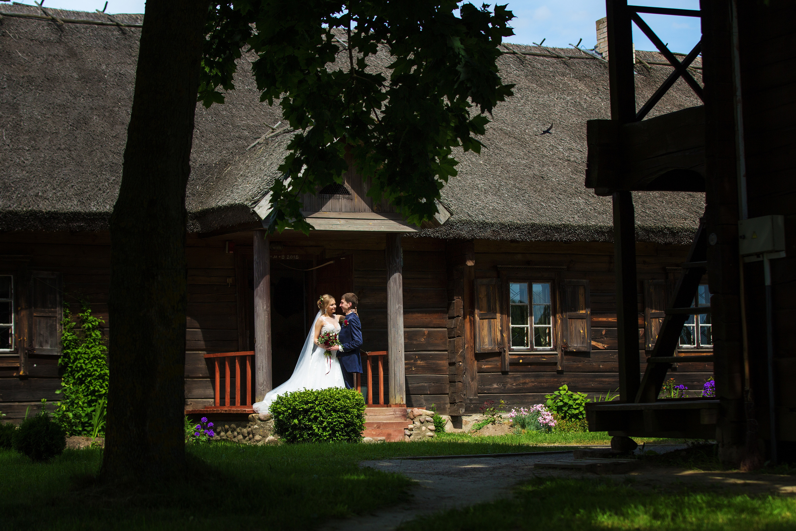 жених с невестой обнимаются на фоне старого деревянного домика