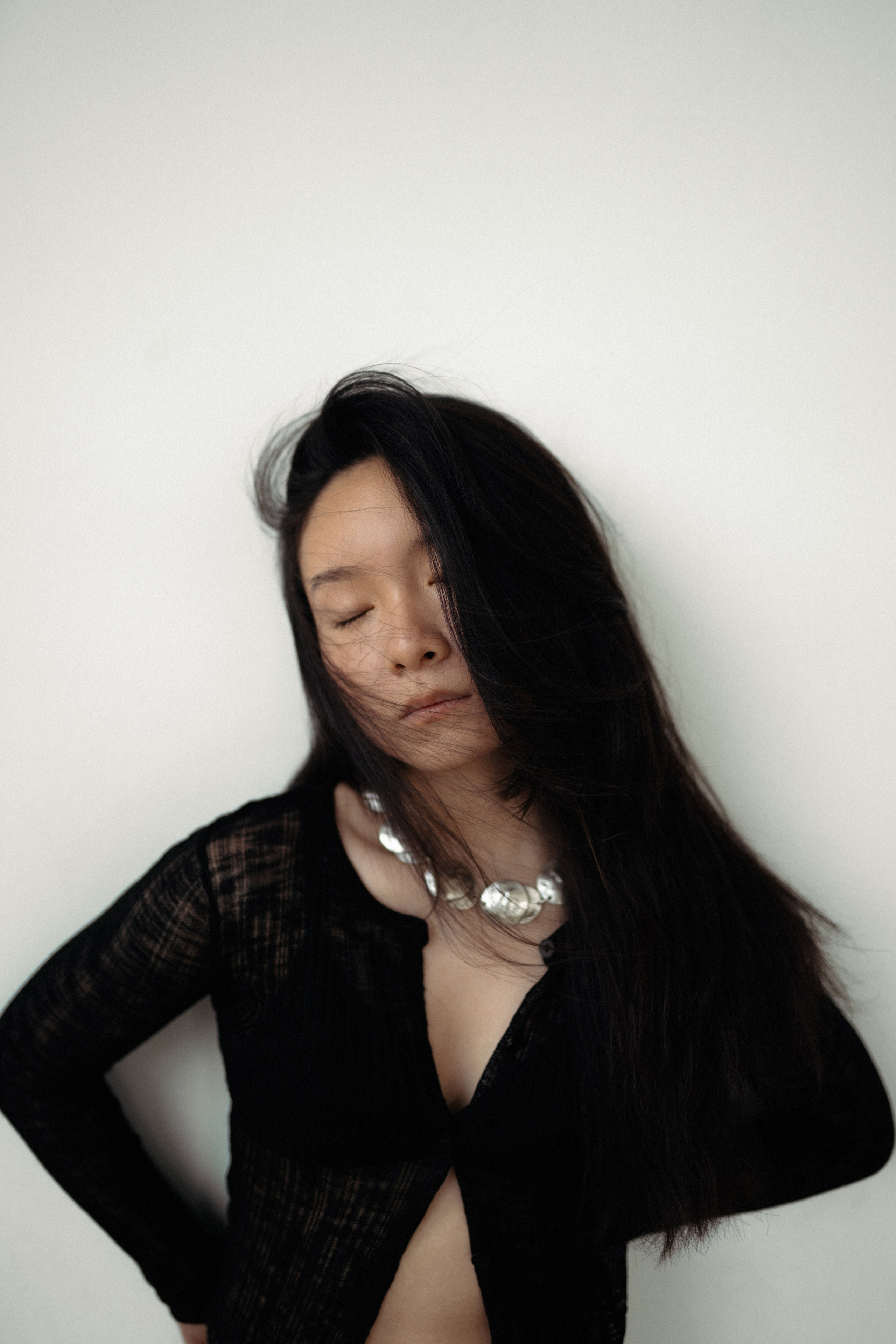 Модель в чёрной одежде и массивном украшении позирует в студии для портретной фотосессии в Санкт-Петербурге