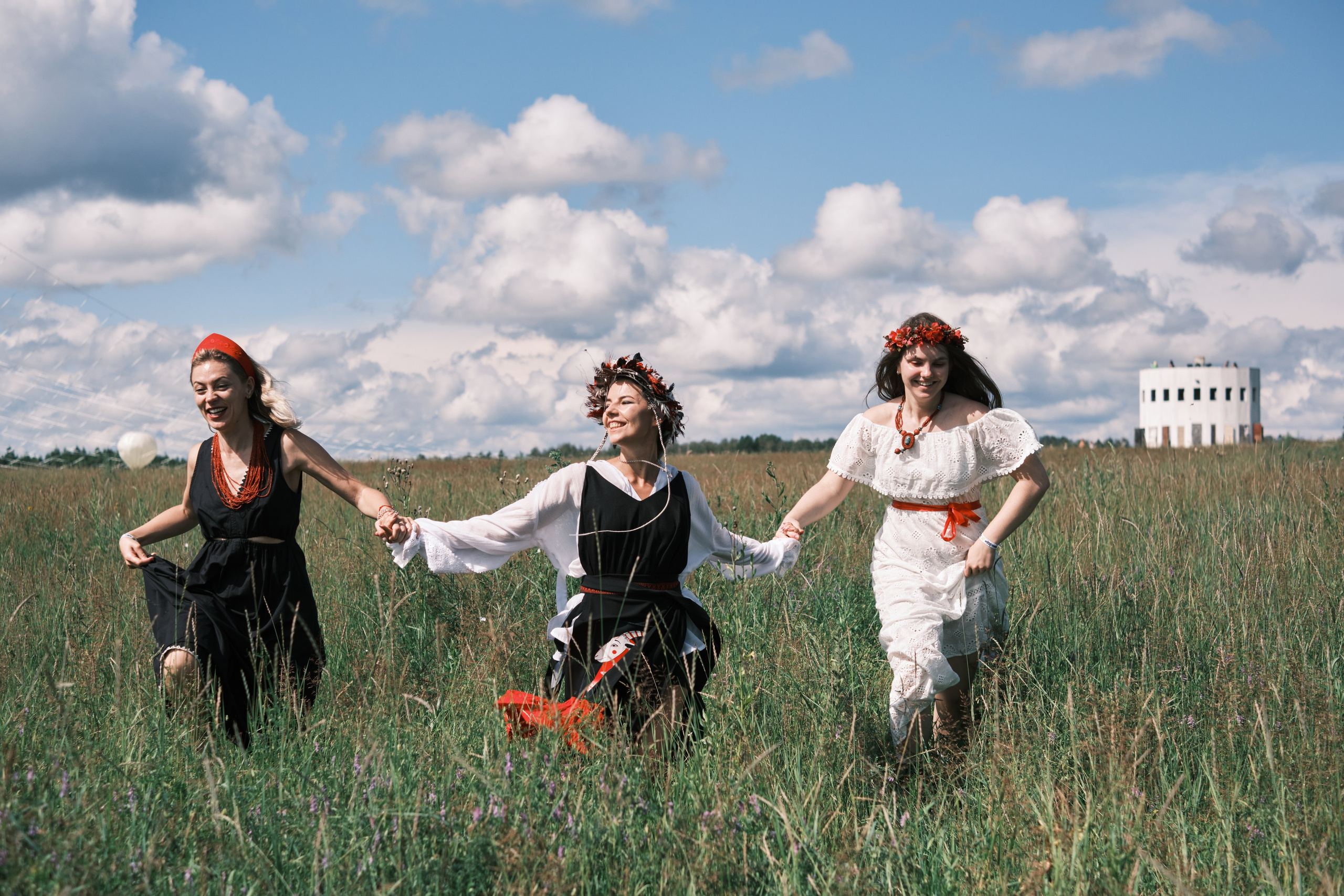 Девушки в русских костюмах с венками на голове бегут по полю на фоне ратонги