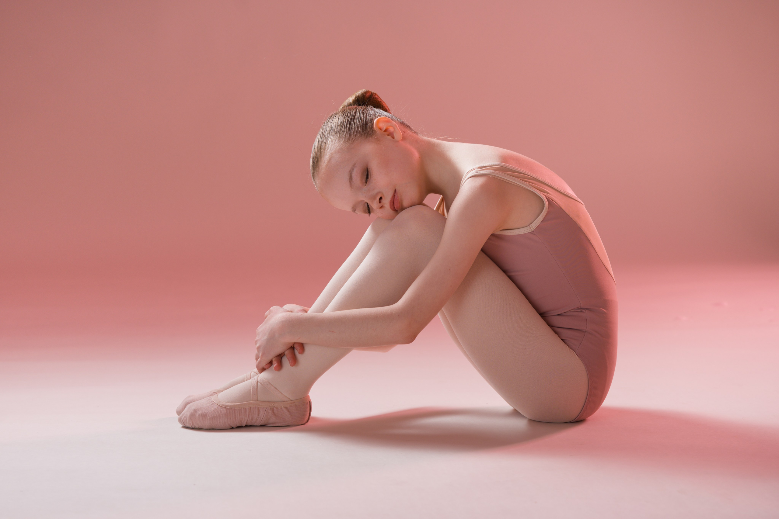 Минималистичный балетный портрет в профиль: девочка сидит, обхватив колени, акцент на линиях и нежной атмосфере спорт-арта