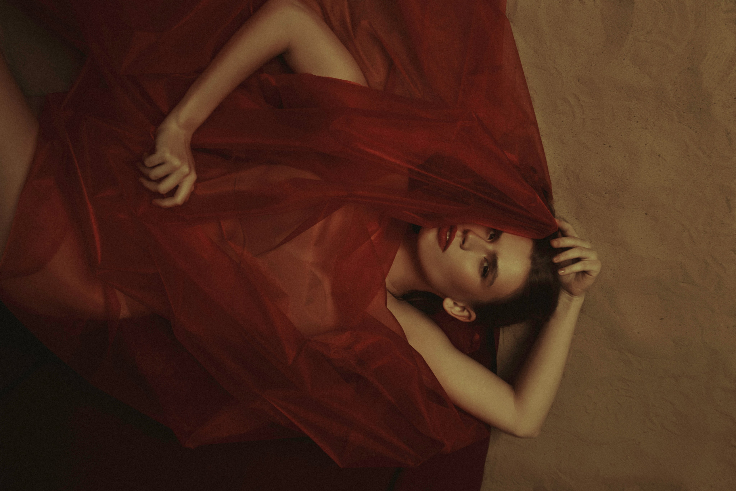 девушка лежит на песке в красной ткани стиль фотографии в стиле работ Рубенса