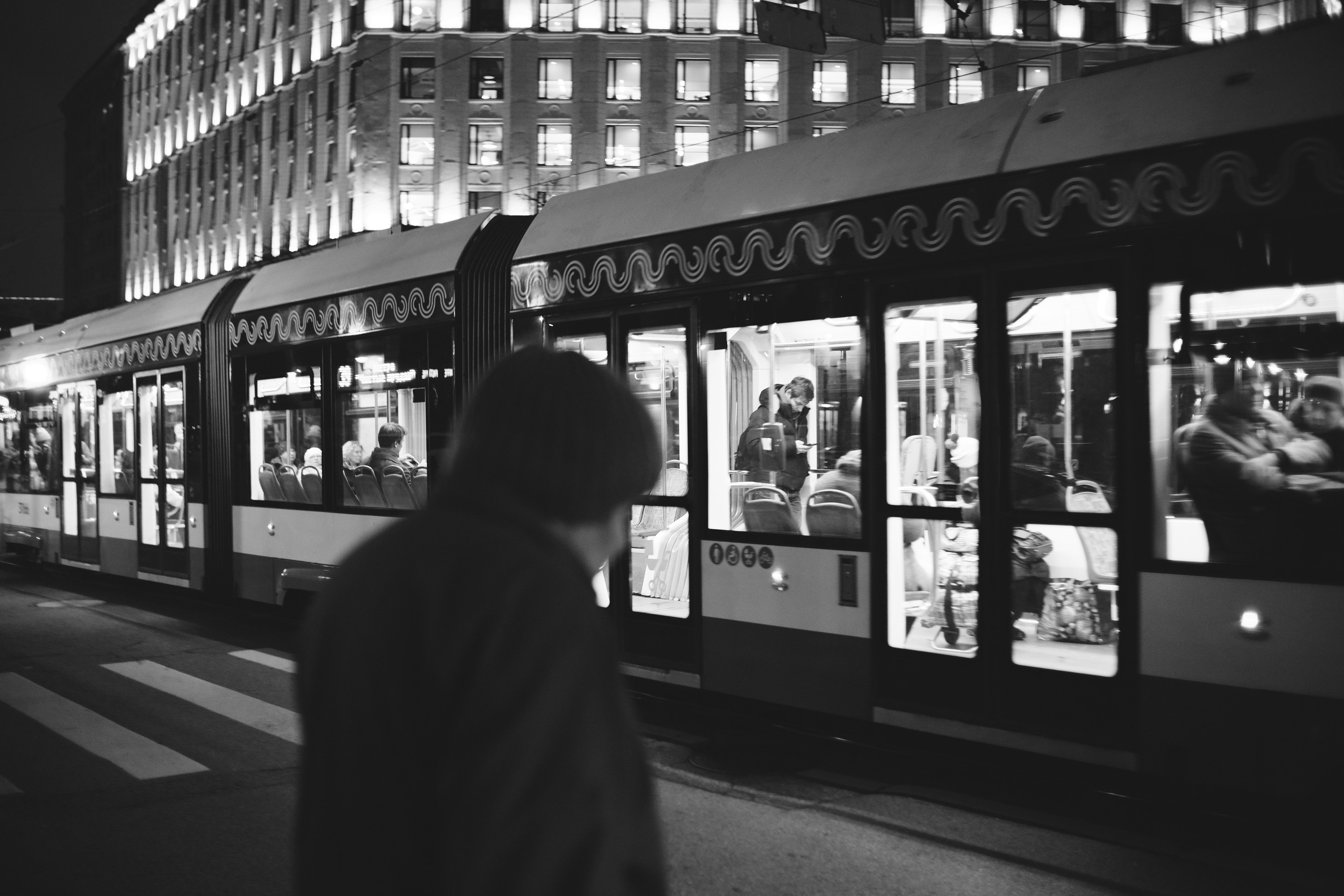 Силуэт бабушки на фоне проезжающего трамвая в Москве