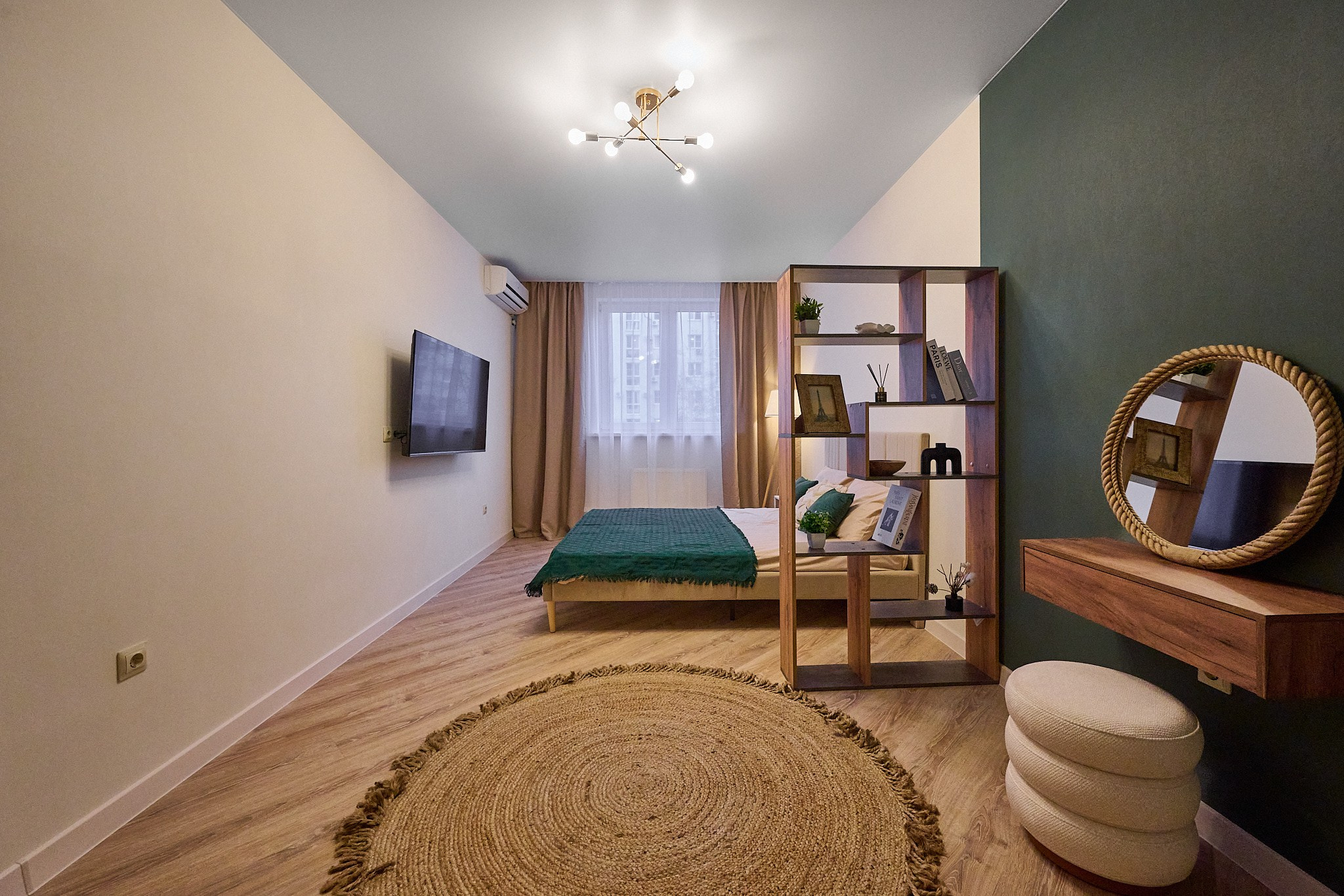 комната с  бело зелеными обоями круглым ковром белым пуфиком круглым зеркалом 