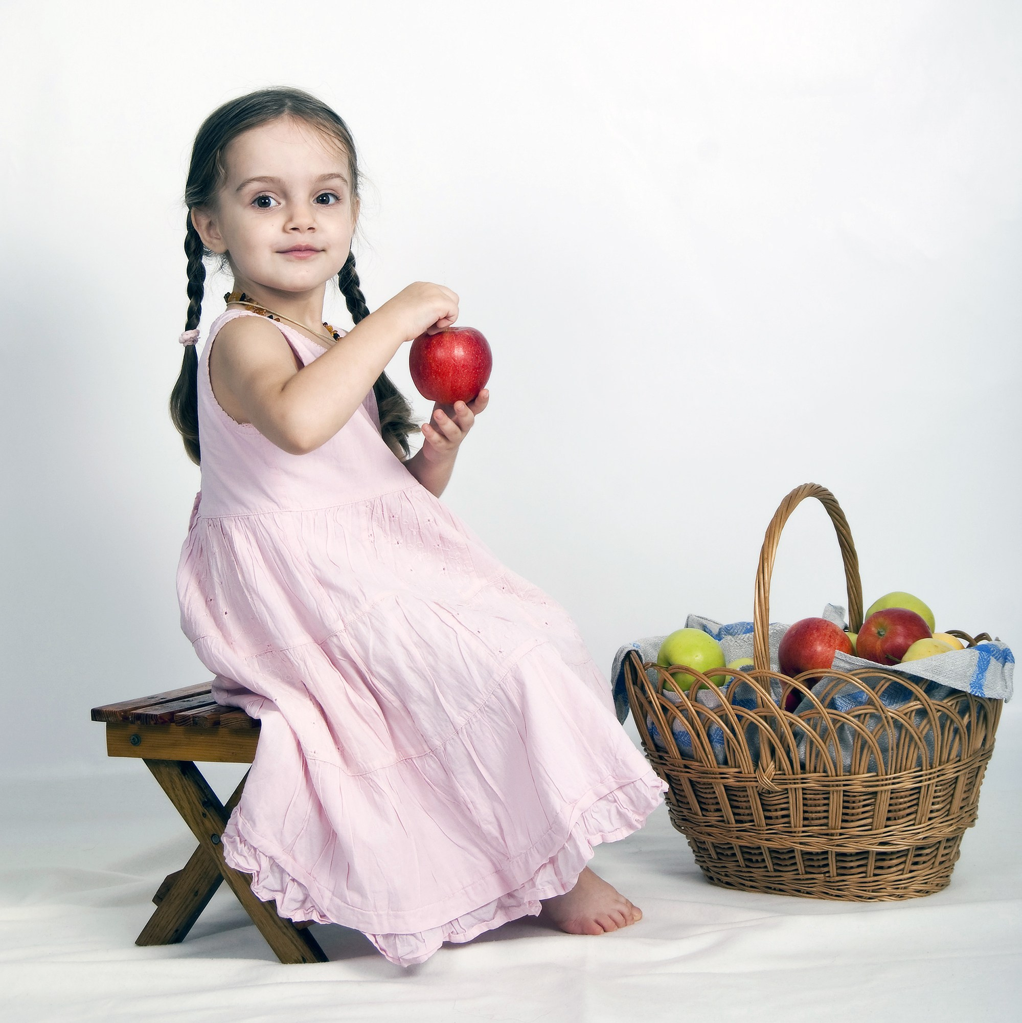 Счастливый ребёнок держит в руках вкусное яблоко в студии