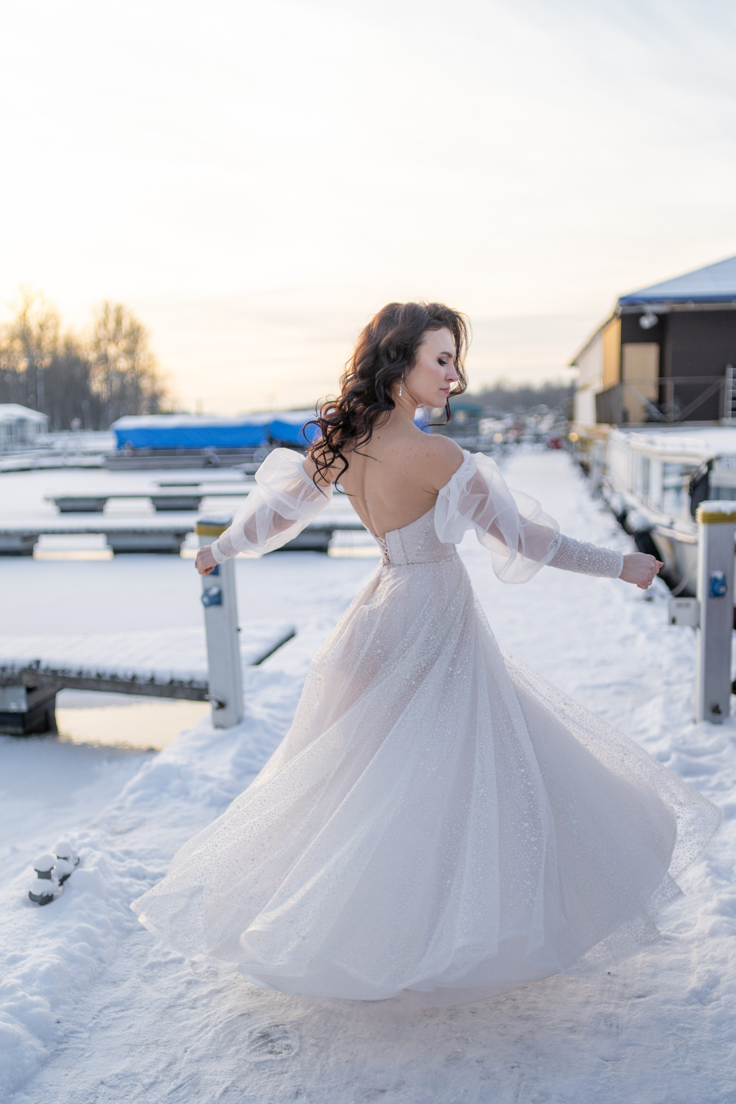 Невеста в свадебном платье танцует на снегу в яхт клубе на закате зимой в Санкт-Петербурге