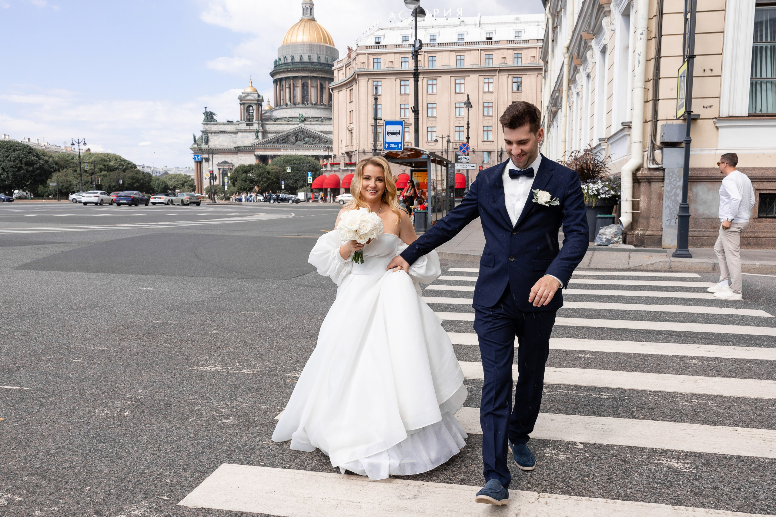 Молодожены на пешеходном переходе к Синему мосту на фоне видны Исаакиевский собор и гостиница Астория