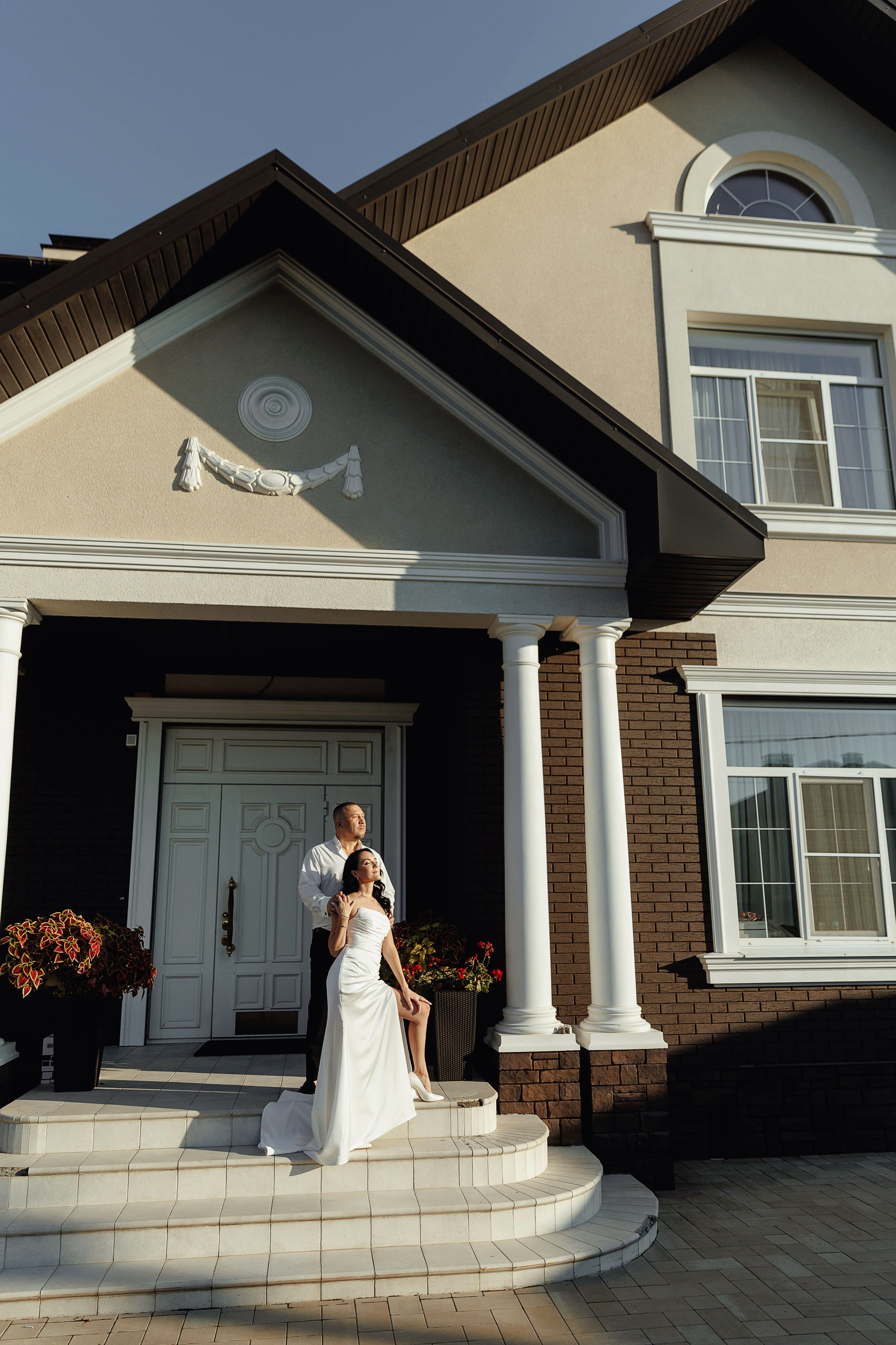 Жених и невеста танцуют на фоне своего дома