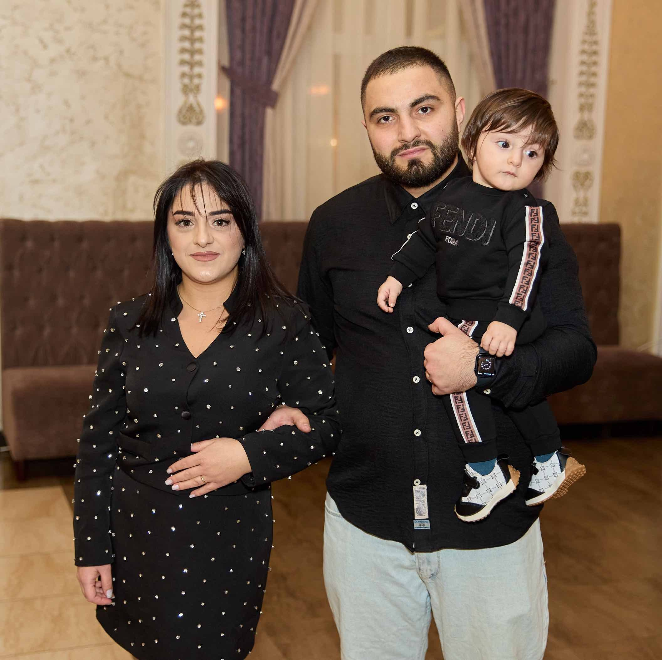 Родители с малышом на руках у дивана в зале ресторана