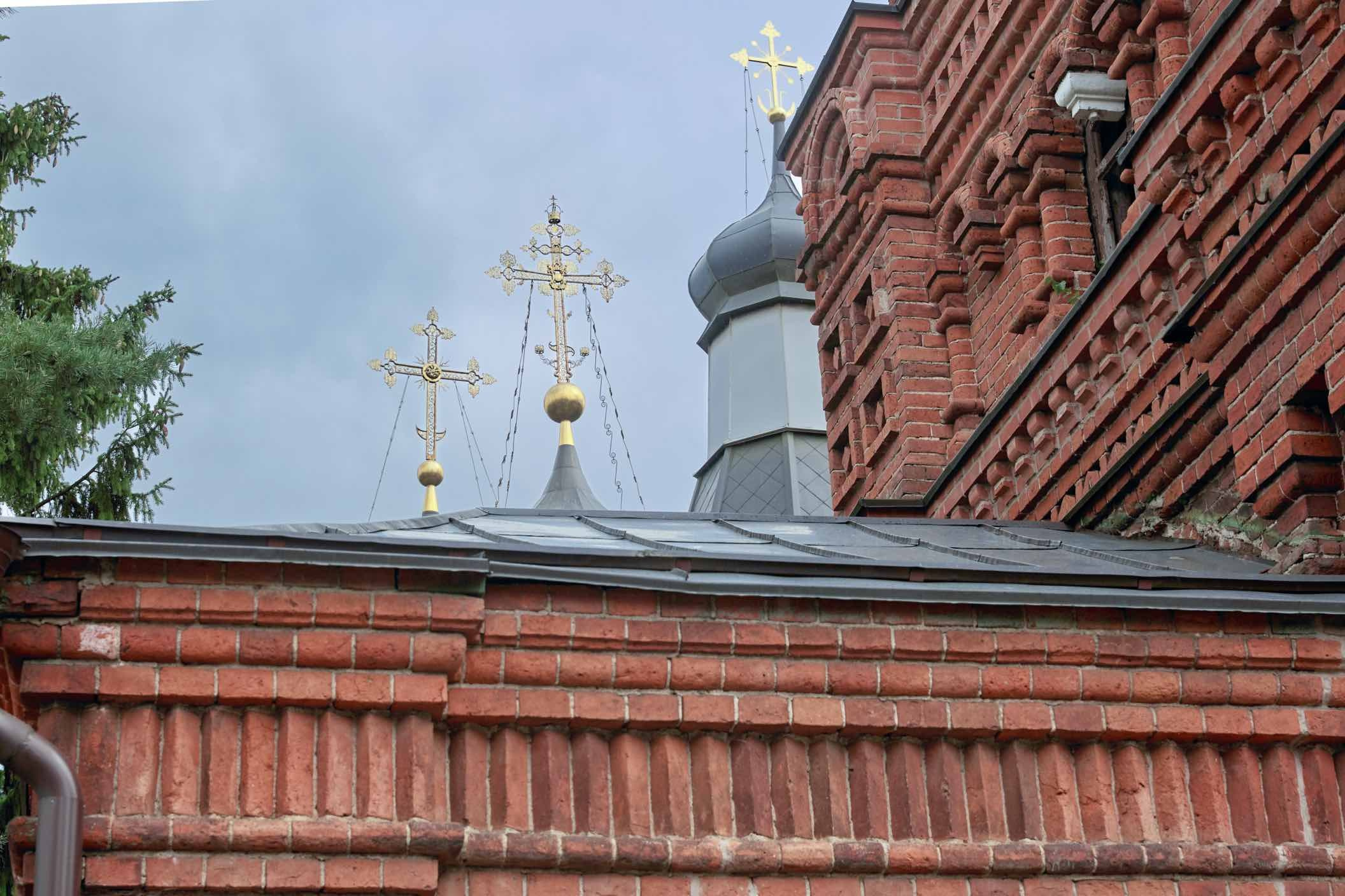 Золочёные кресты, купола краснокирпичного храма, где проходит венчание
