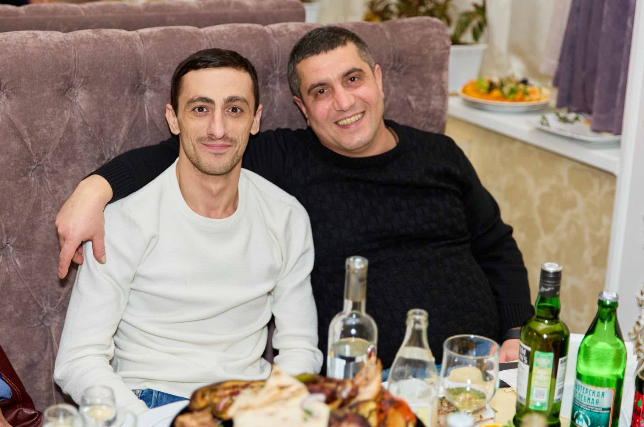 Двое мужчин обнялись за столом на празднике