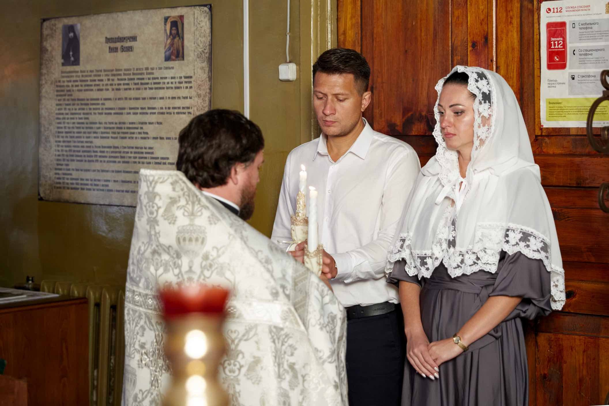 Священник подаёт зажжённые свечи паре перед началом венчания