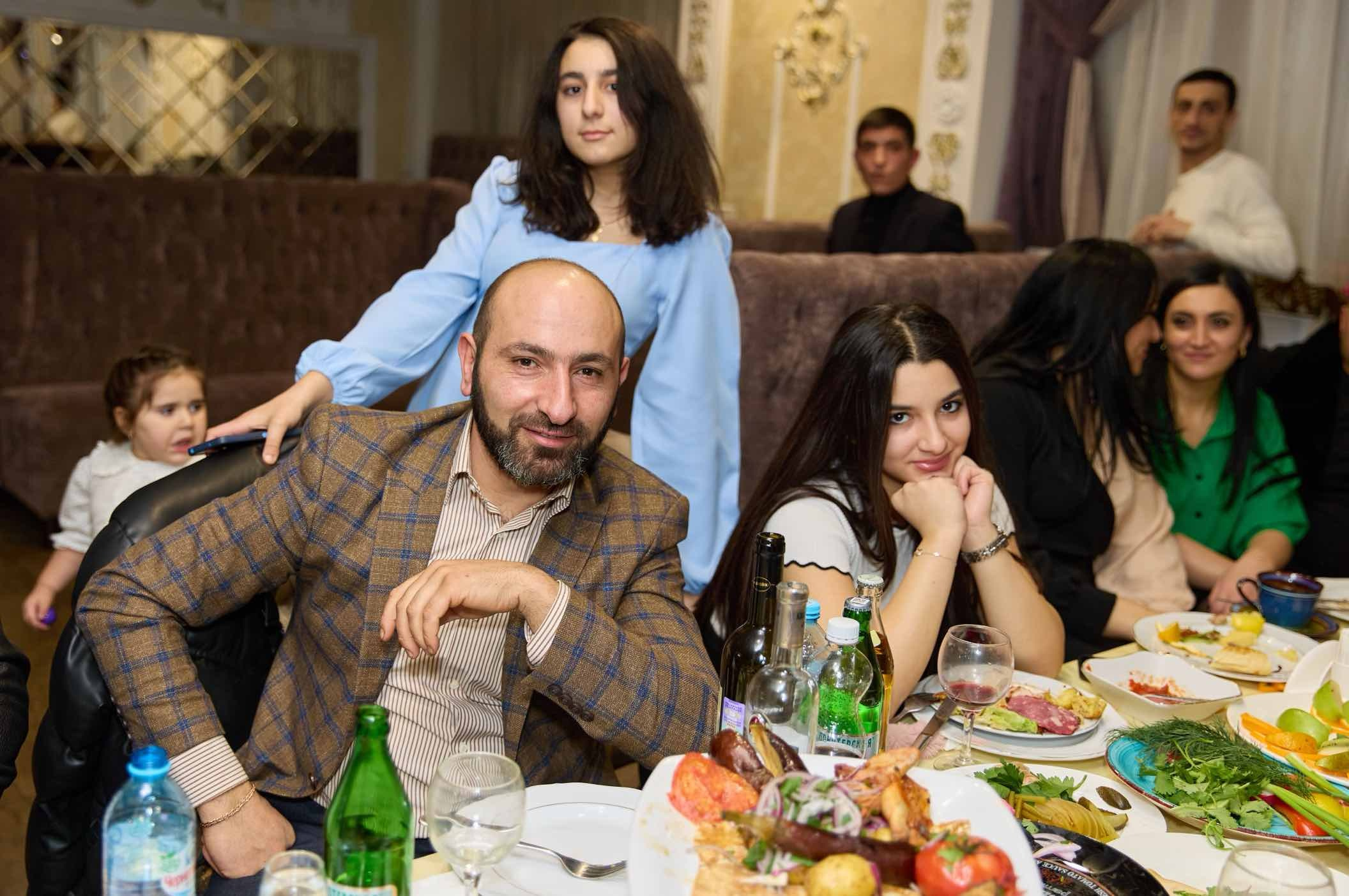 Гость с дочерью за плечами и гостьи за столом