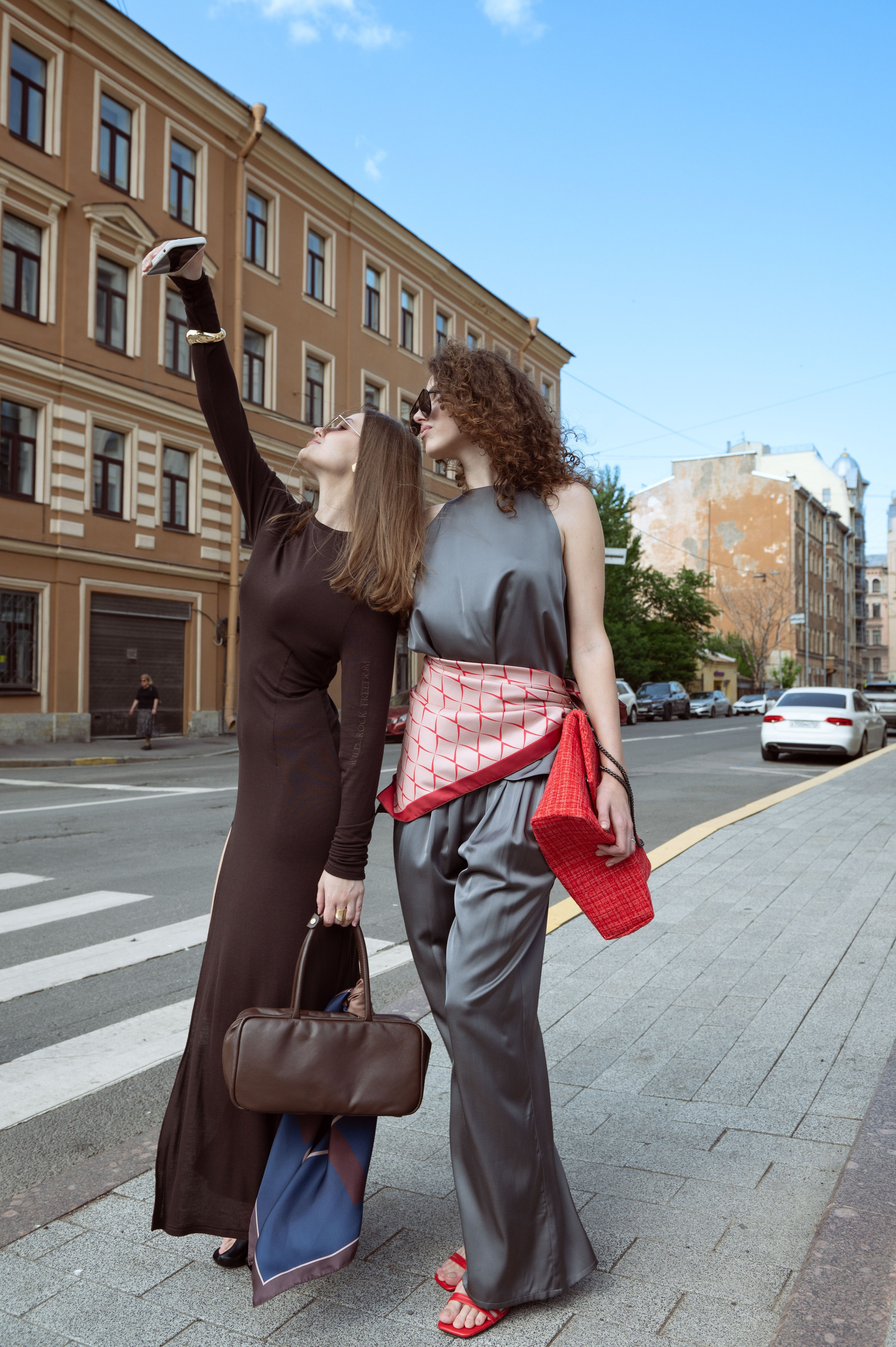 Две красивые девушки в дизайнерской одежде и шелковых дизайнерских платках делают сэлфи