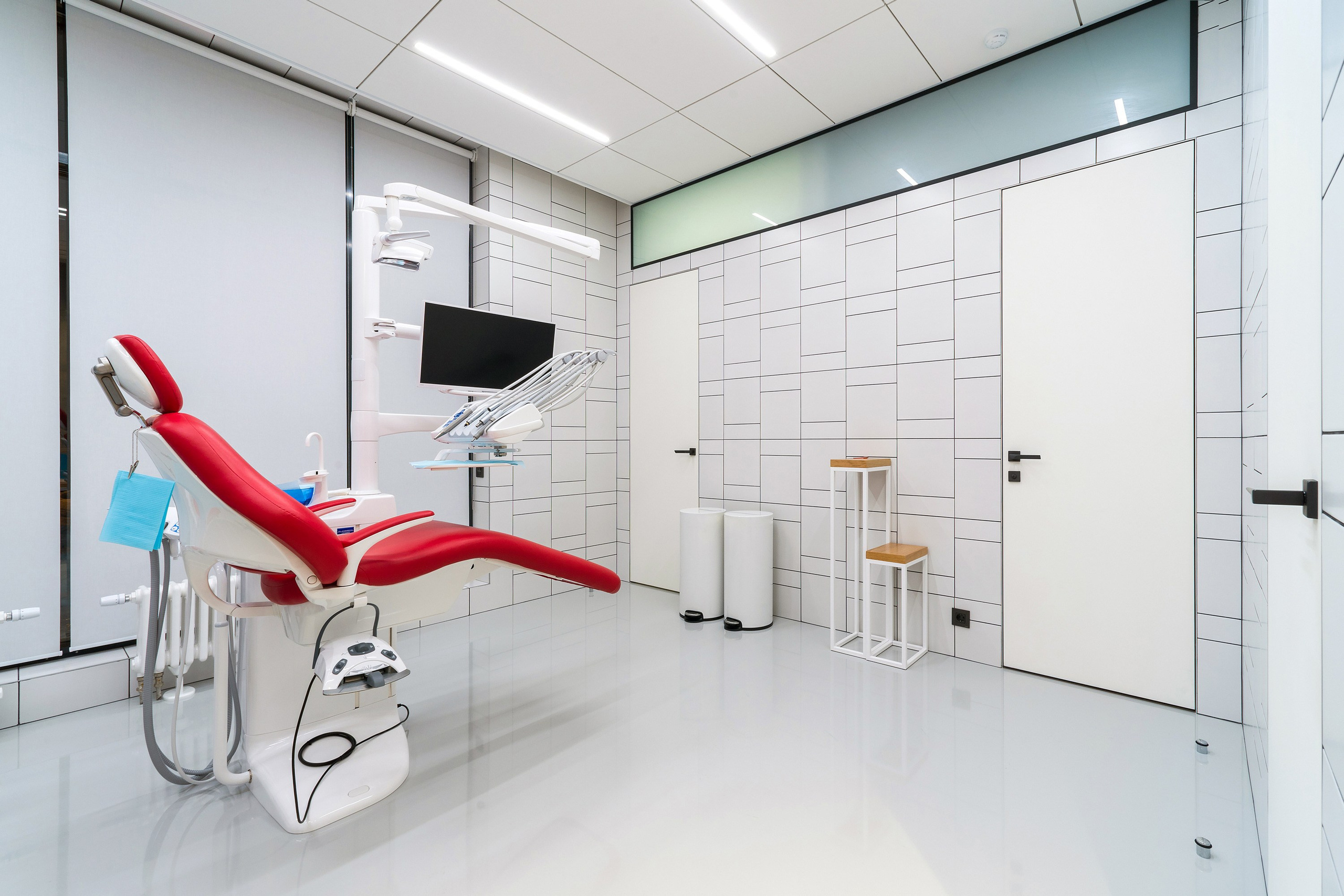 дизайн интерьера стоматологической клиники выполнен в современном минималистичном стиле с теплой домашней атмосферой. Текстуры дерева, наливной пол, яркие акценты, чистота линий, модульная сетка, стеклянные перегородки