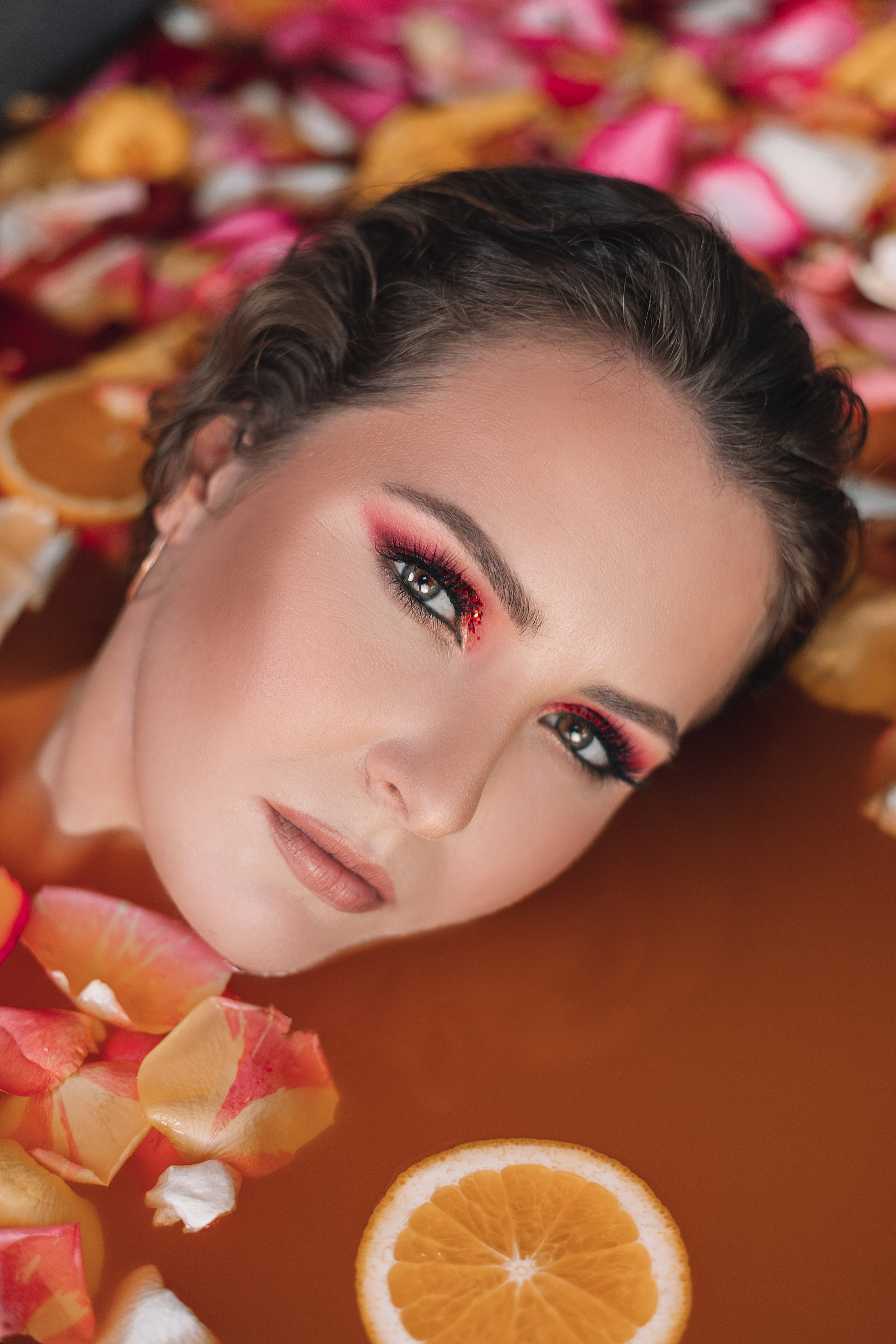 Девушка в ванной с лепестками цветов и апельсинами