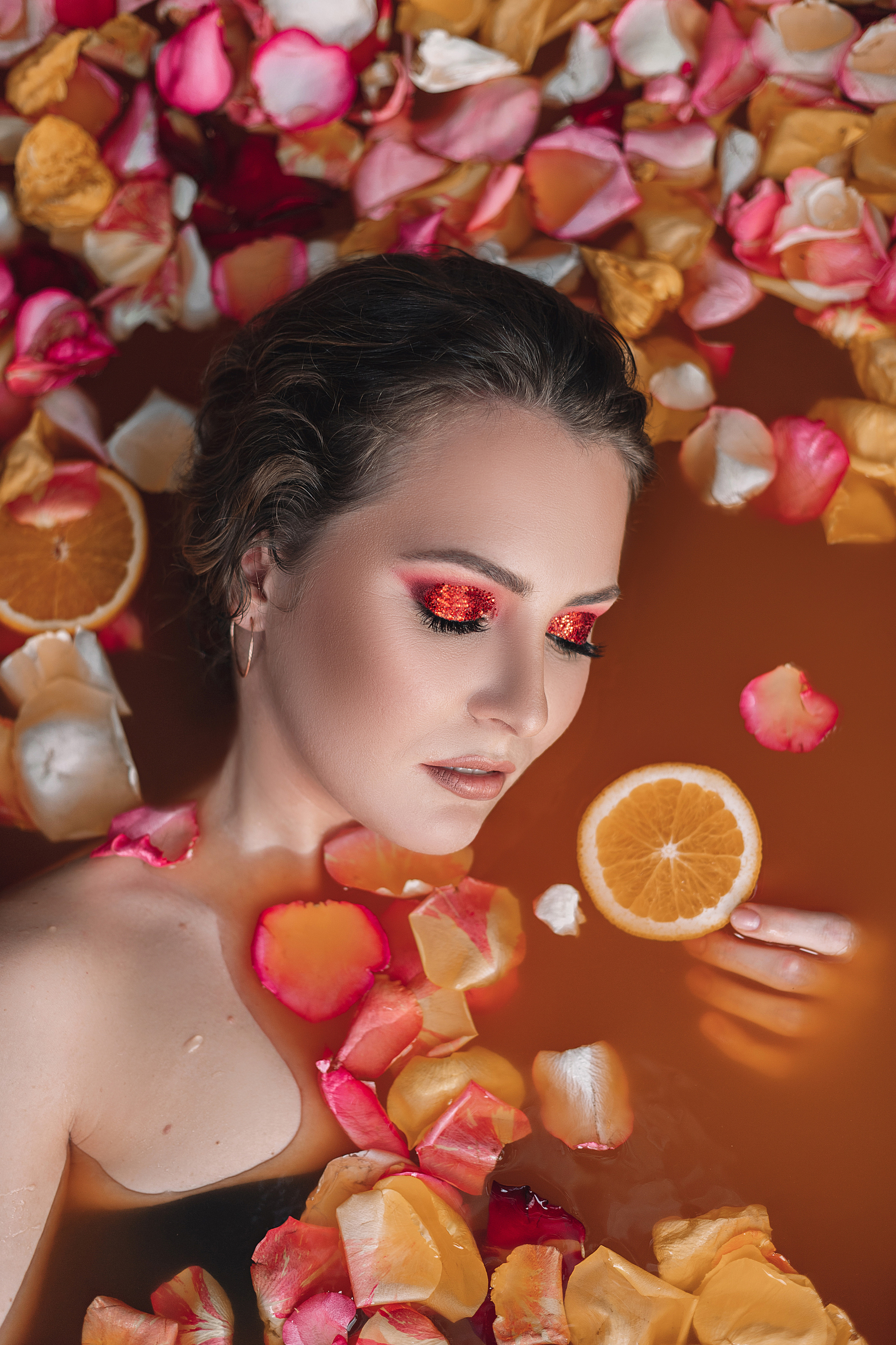 Девушка в ванной с лепестками цветов и апельсинами