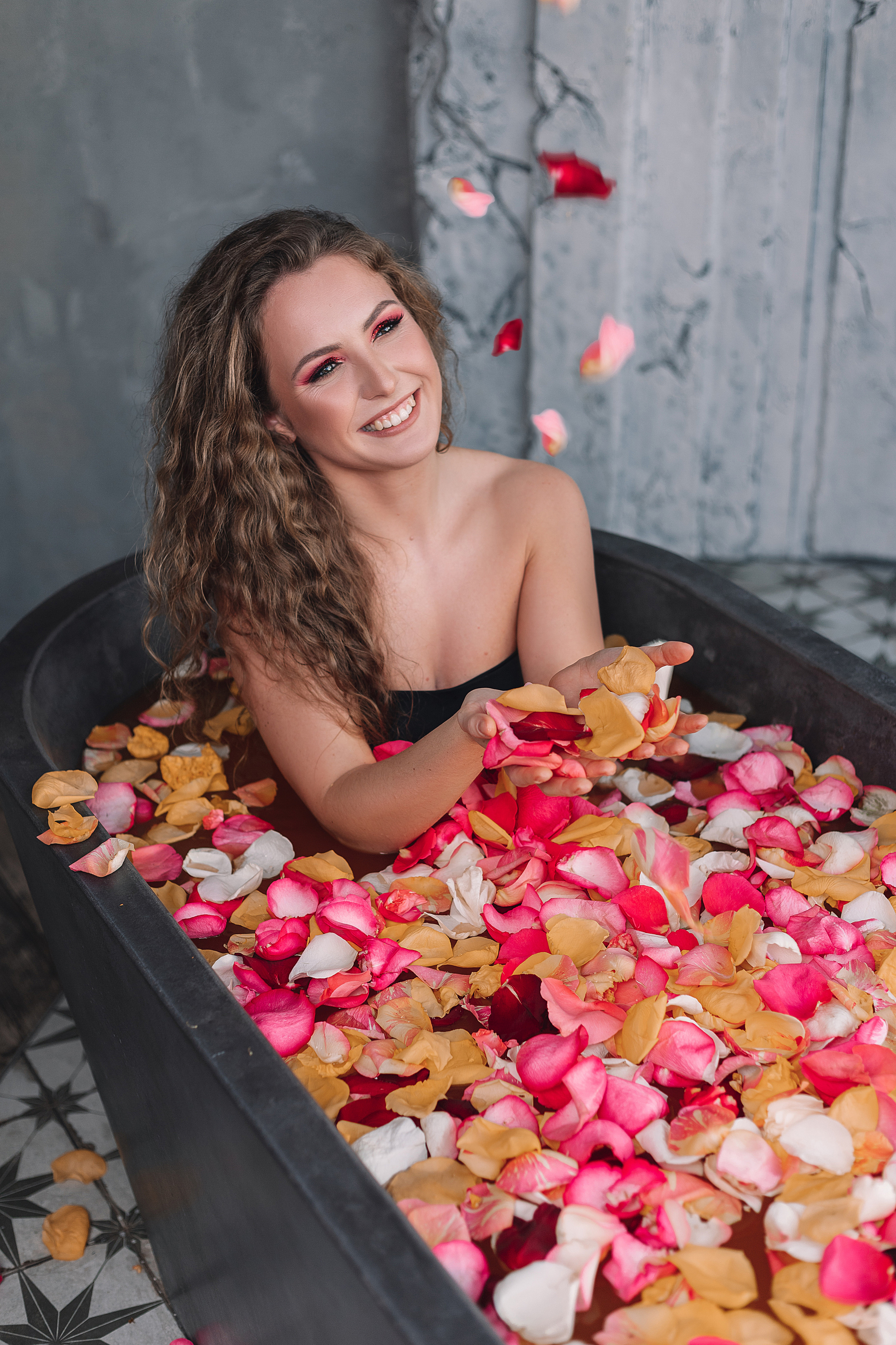 Девушка в ванной с лепестками цветов и апельсинами