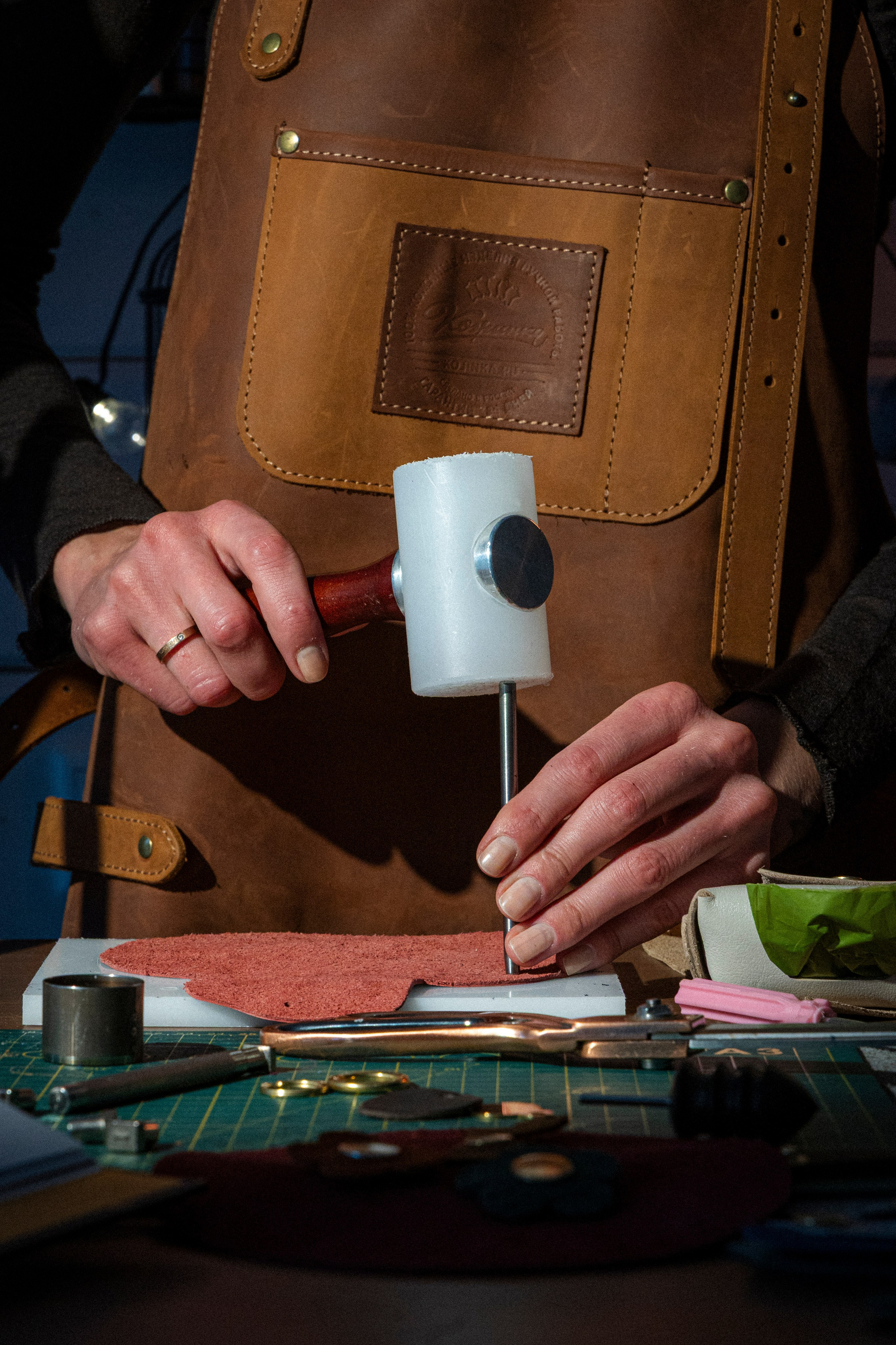 Крупно: пальцы держат пробойник, пробивают отверстия в коже.