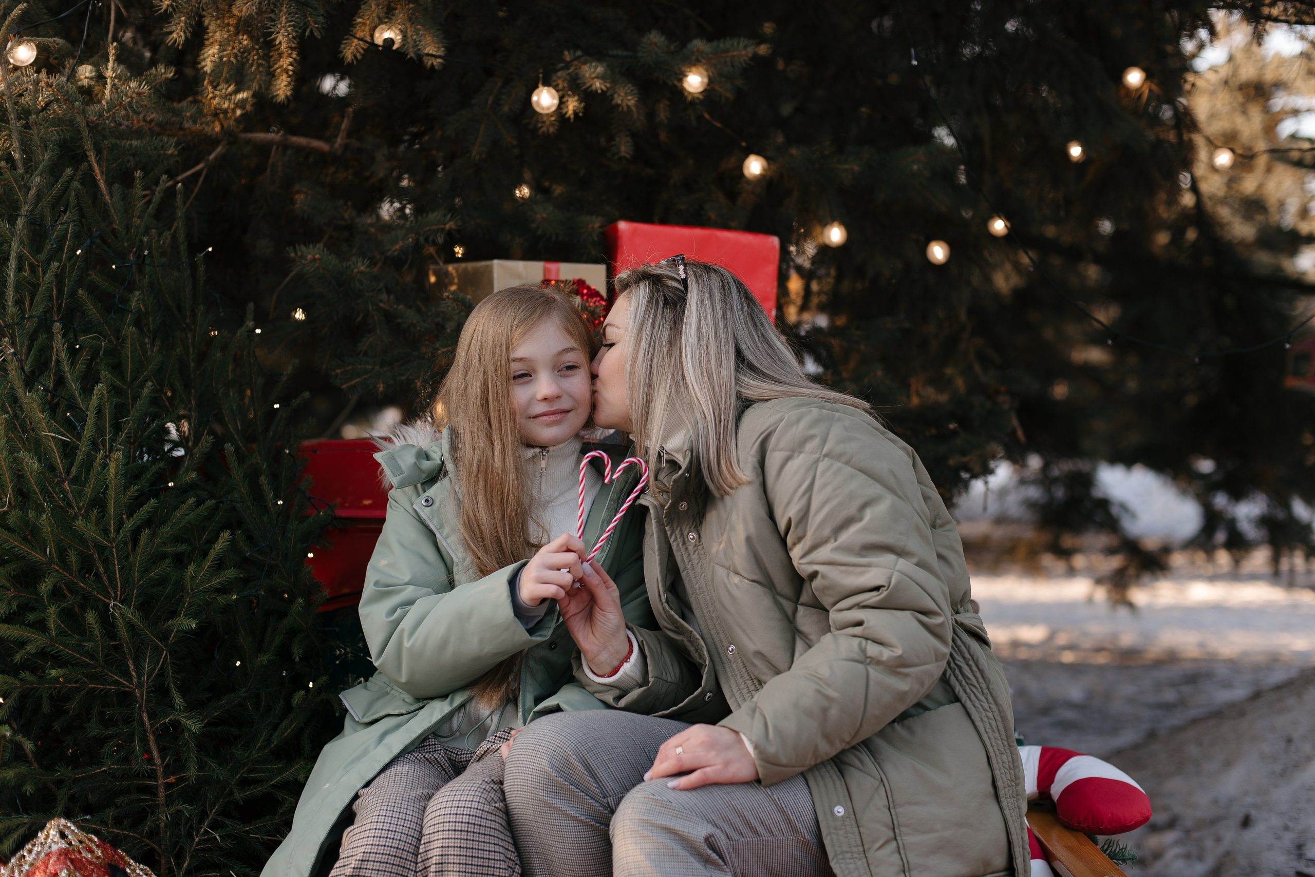 Фотосессия: мама целует дочку у новогодней елки.