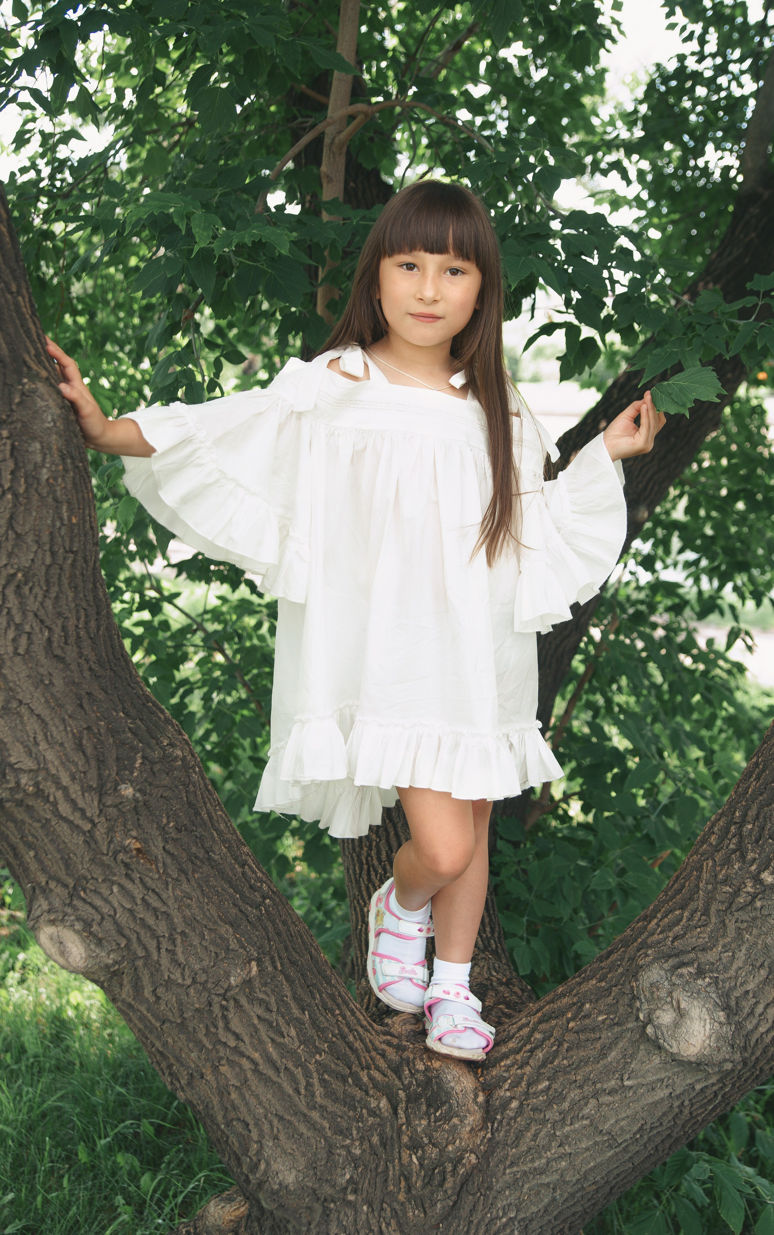 Детская фотосессия летом - девочка стоя на дереве