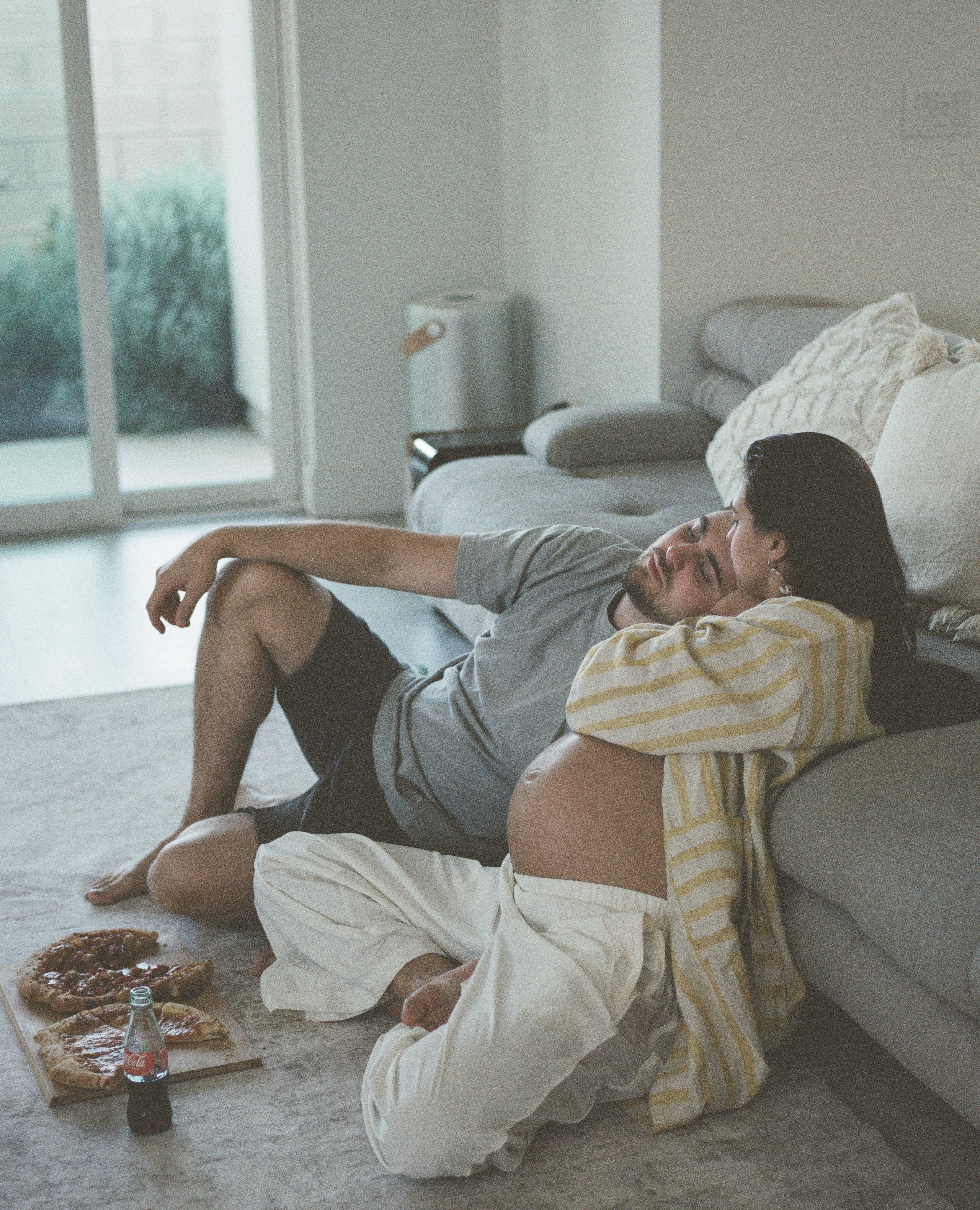 A couple in Los Angeles sitting on the floor of their apartment and eating pizza