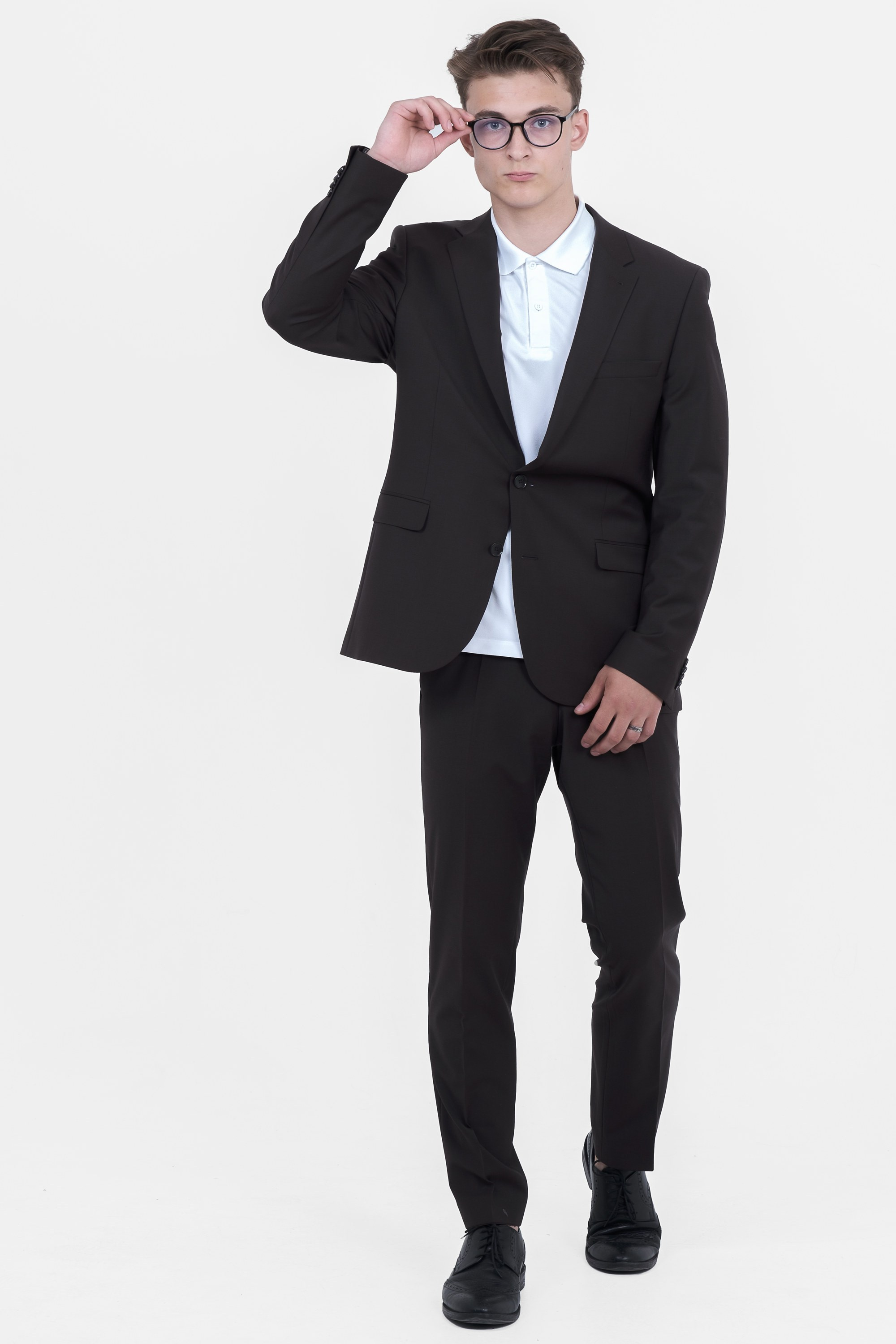 Молодой человек идет в чёрном костюме в очках и чёрных ботинках.  Фото для маркетплейсов