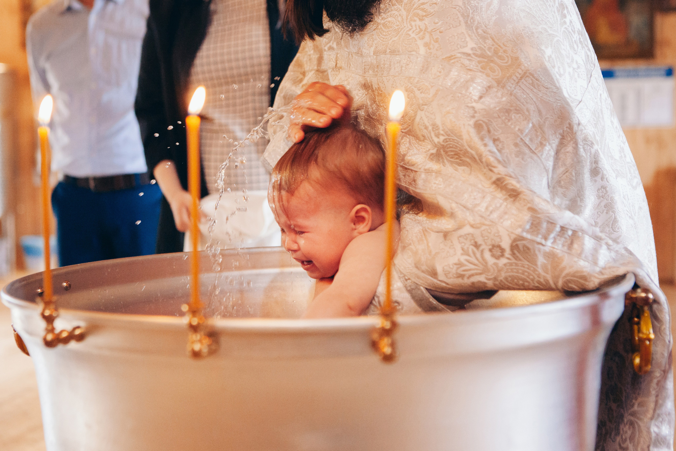 Погружение ребенка в купель на крещении в церкви в Москве