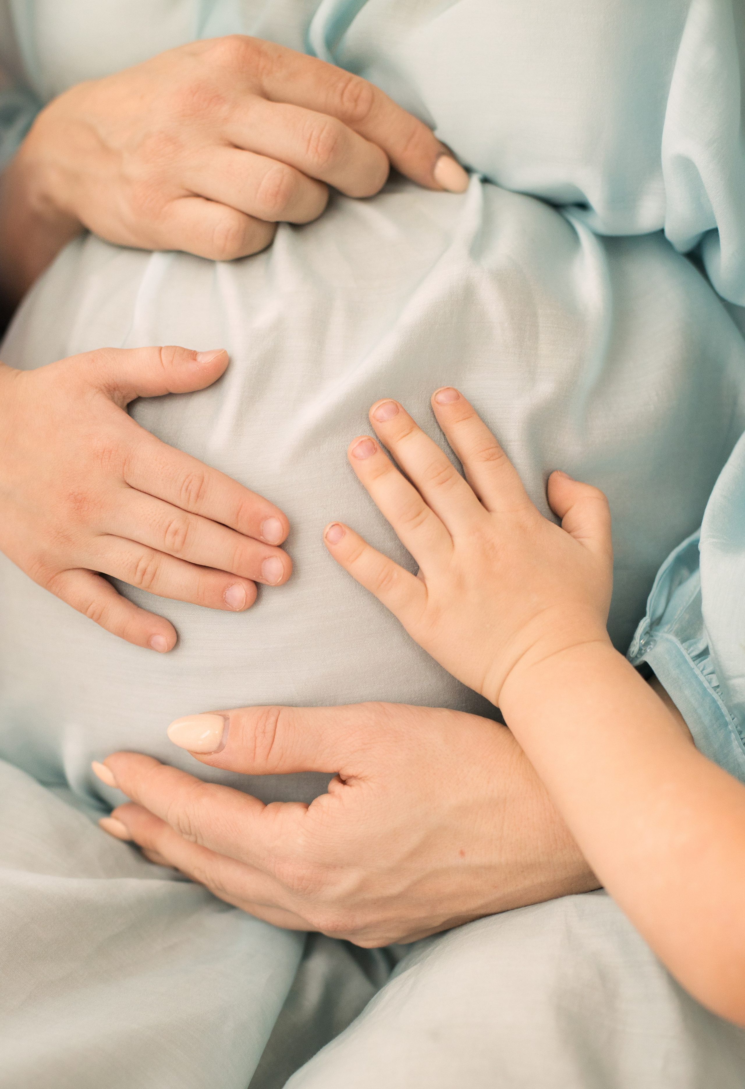 Детские ручки гладят мамин беременный животик, крупный план.