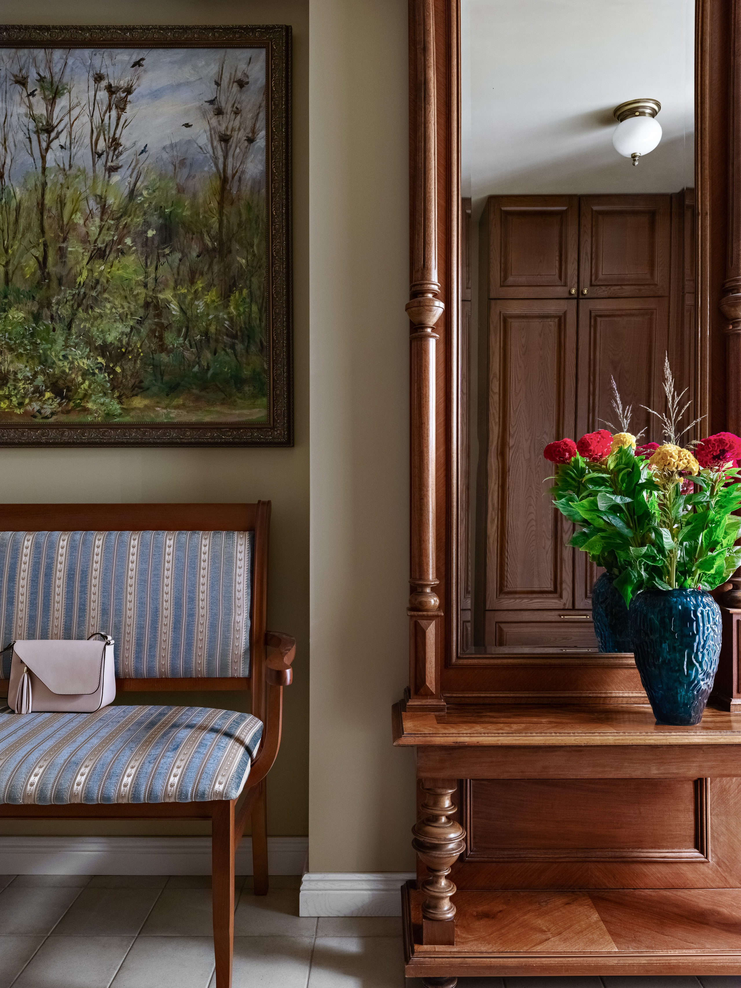 Интерьер прихожей с мягкой лавкой и розовой сумкой, большим зеркалом в деревянной раме и букетом в синей вазе; уютный современный дизайн, разработанный Юлией Капункиной и Альбиной Терещенко, стилист Алина Нелень, фотограф Сергей Денисенко.