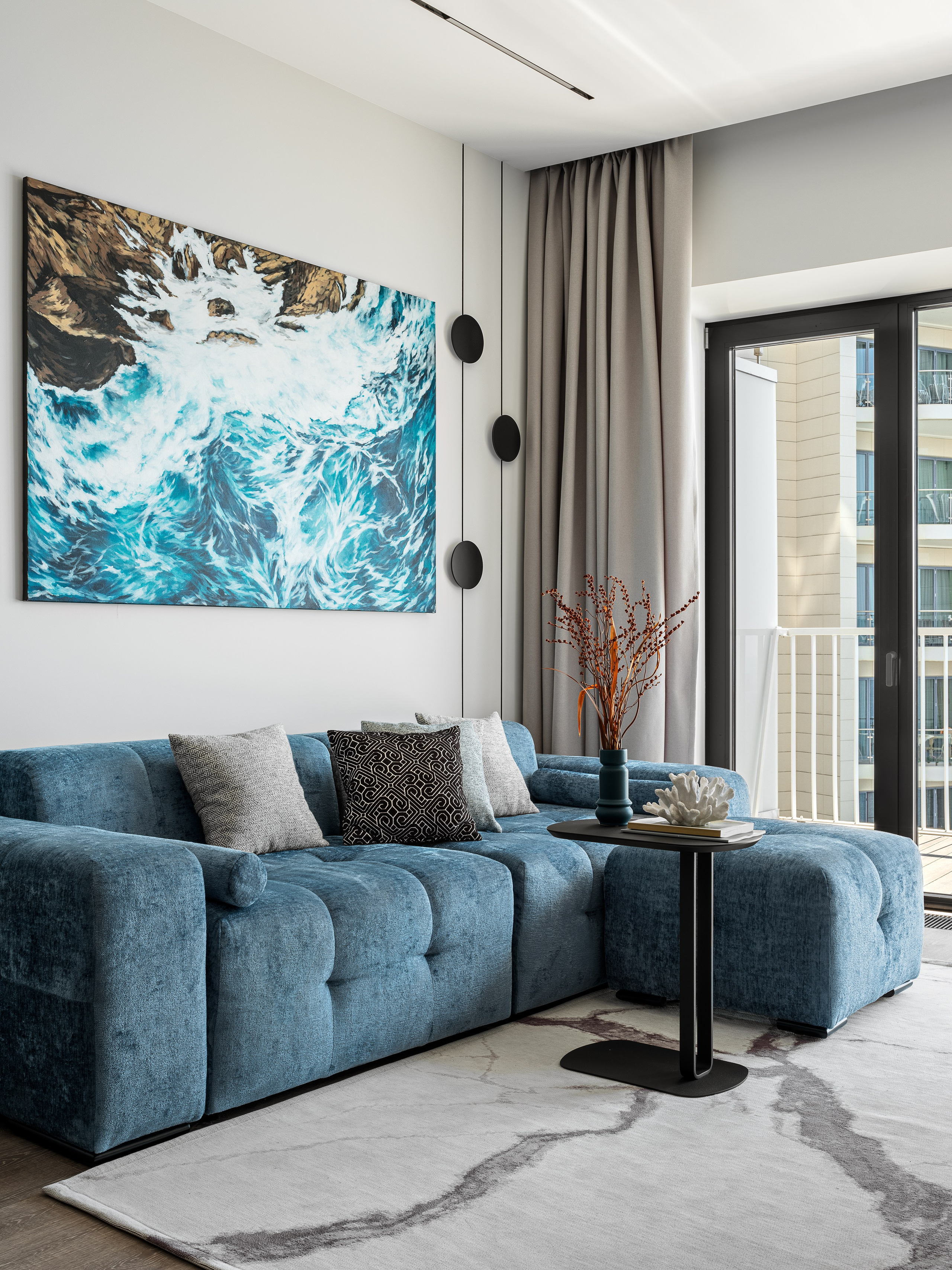 Дизайнерский интерьер зоны отдыха с панорамными окнами, мягким диваном и акцентной картиной в морском стиле; стильное решение пространства авторства Рената Байчукова и Алеси Кириенко, стилист Екатерина Ракитина, фото Сергей Денисенко.