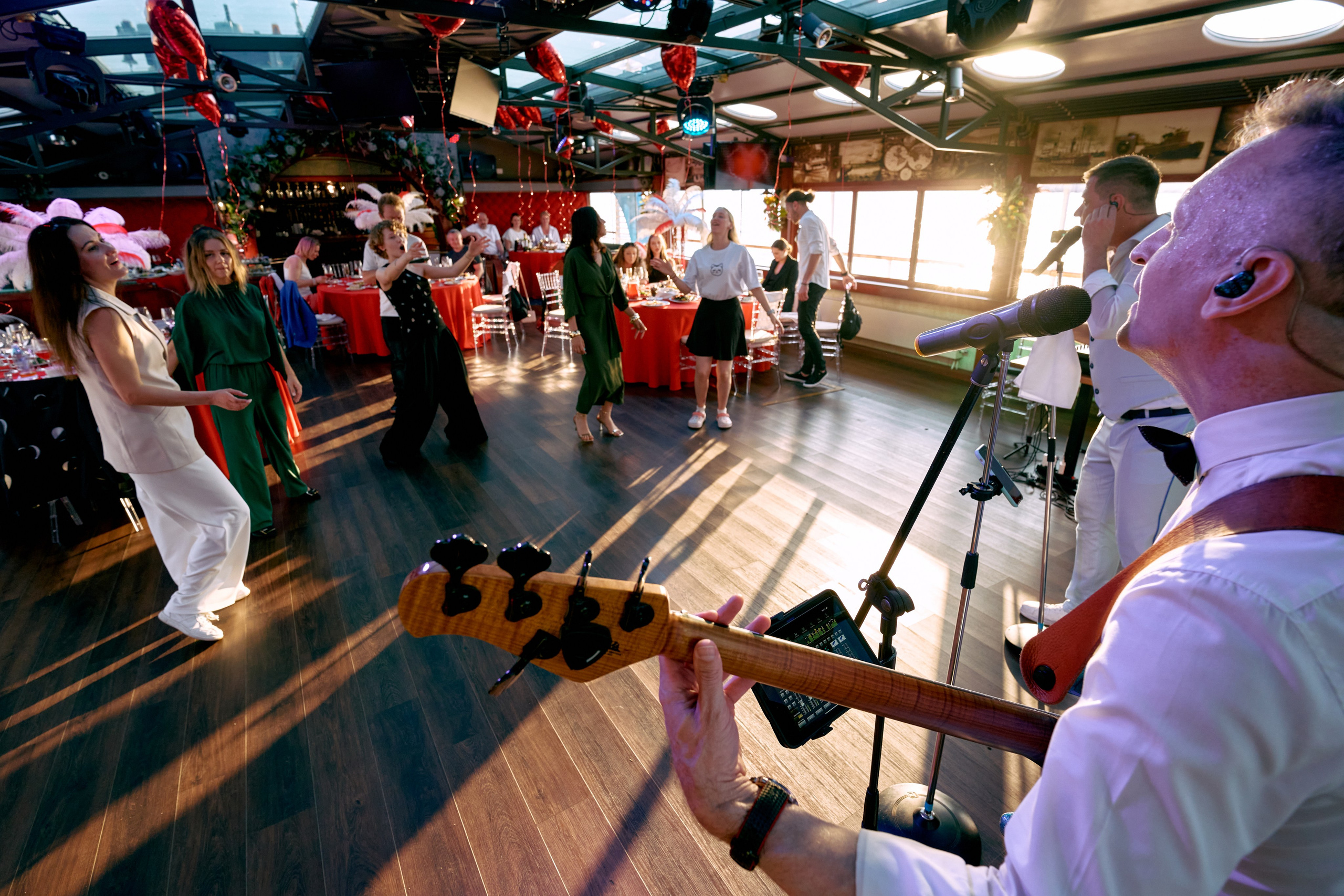 Музыкальная группа играет на сцене в зале со световыми эффектами и красными шарами