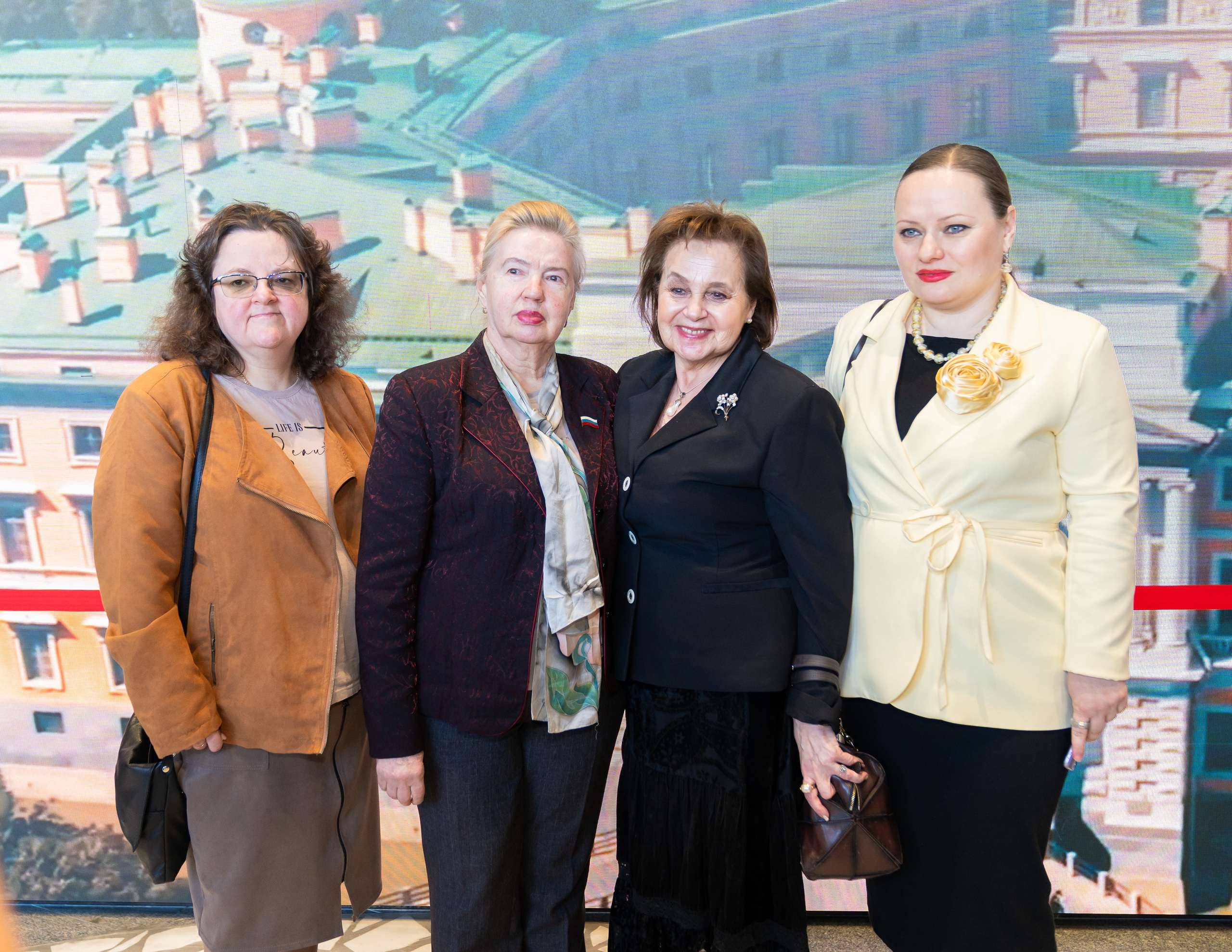 Участницы Дня местного самоуправления Санкт-Петербург. Четыре женщины позируют вместе на фоне панорамы города. Фотограф Евгений Мальцев.