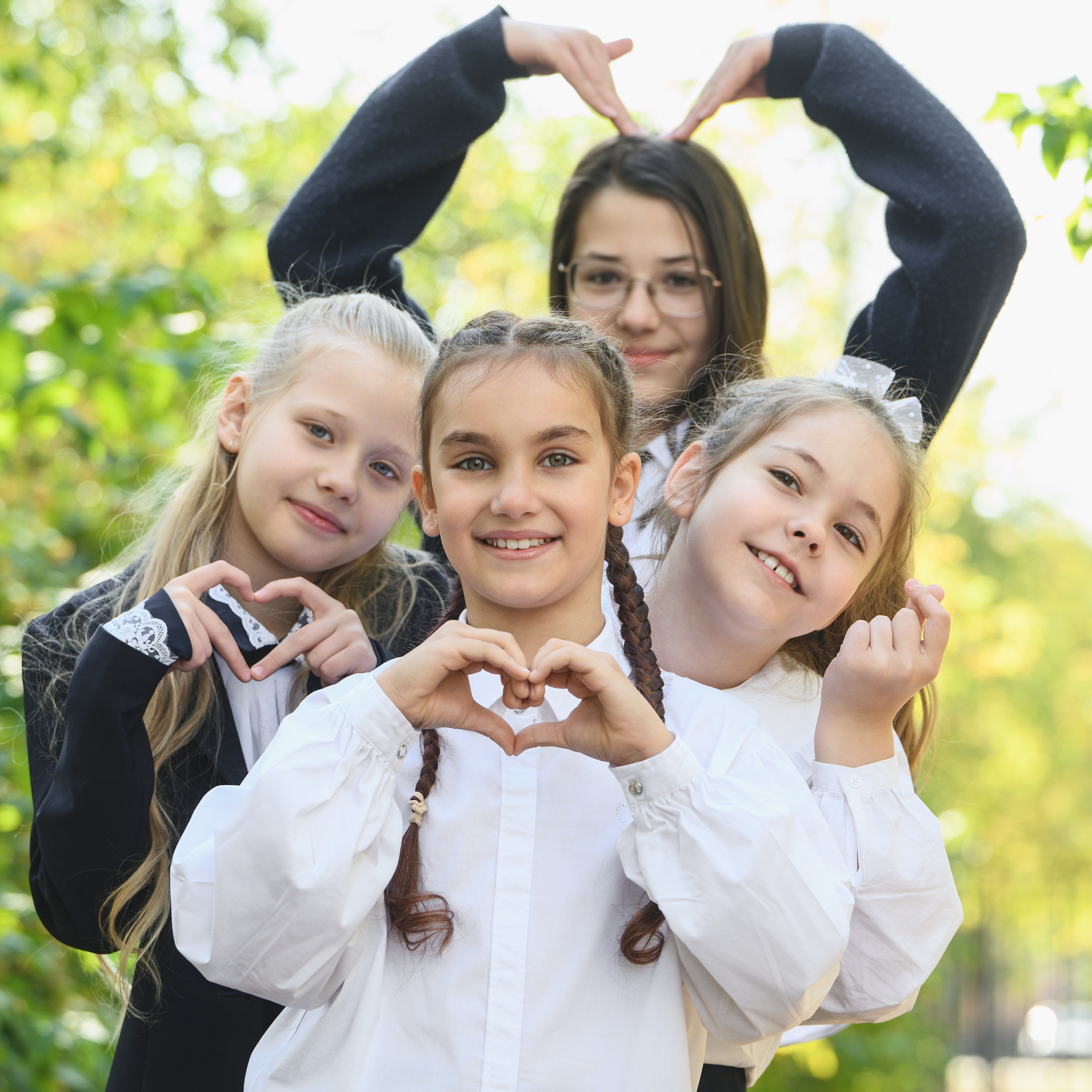 Четыре школьницы показывают сердечко руками