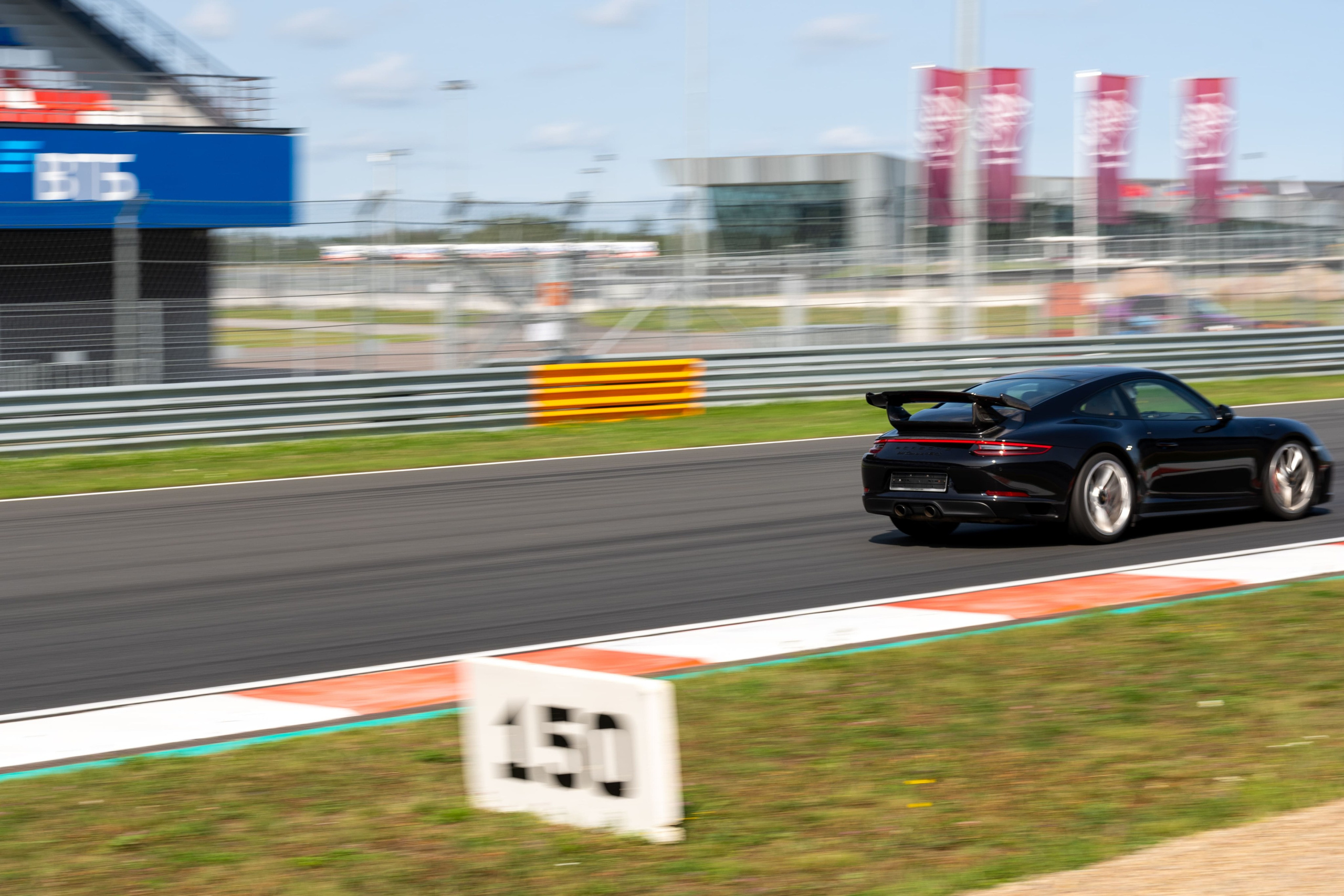 Черный Porsche 911 на высокой скорости на трассе Игора Драйв, спортивный фотограф Санкт-Петербург.