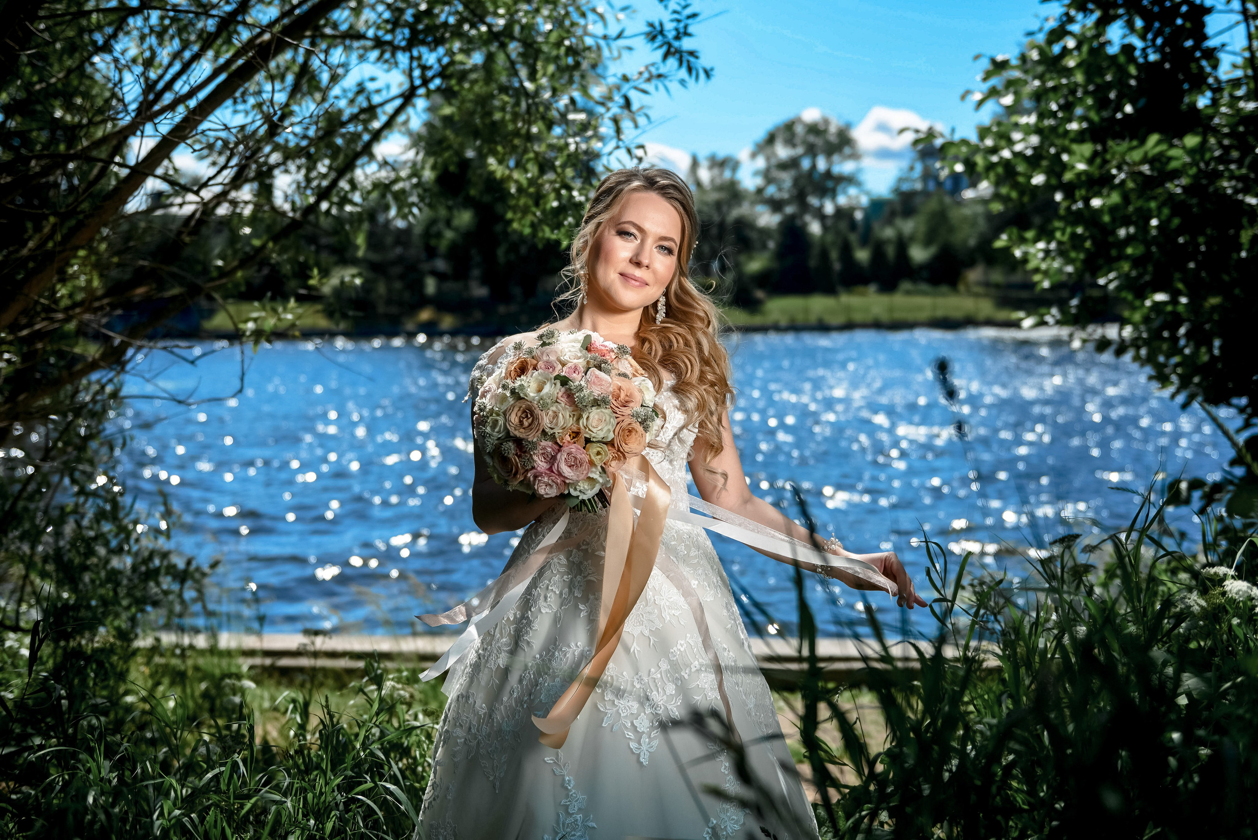 Портрет красивой невесты в солнечный день на фоне озера