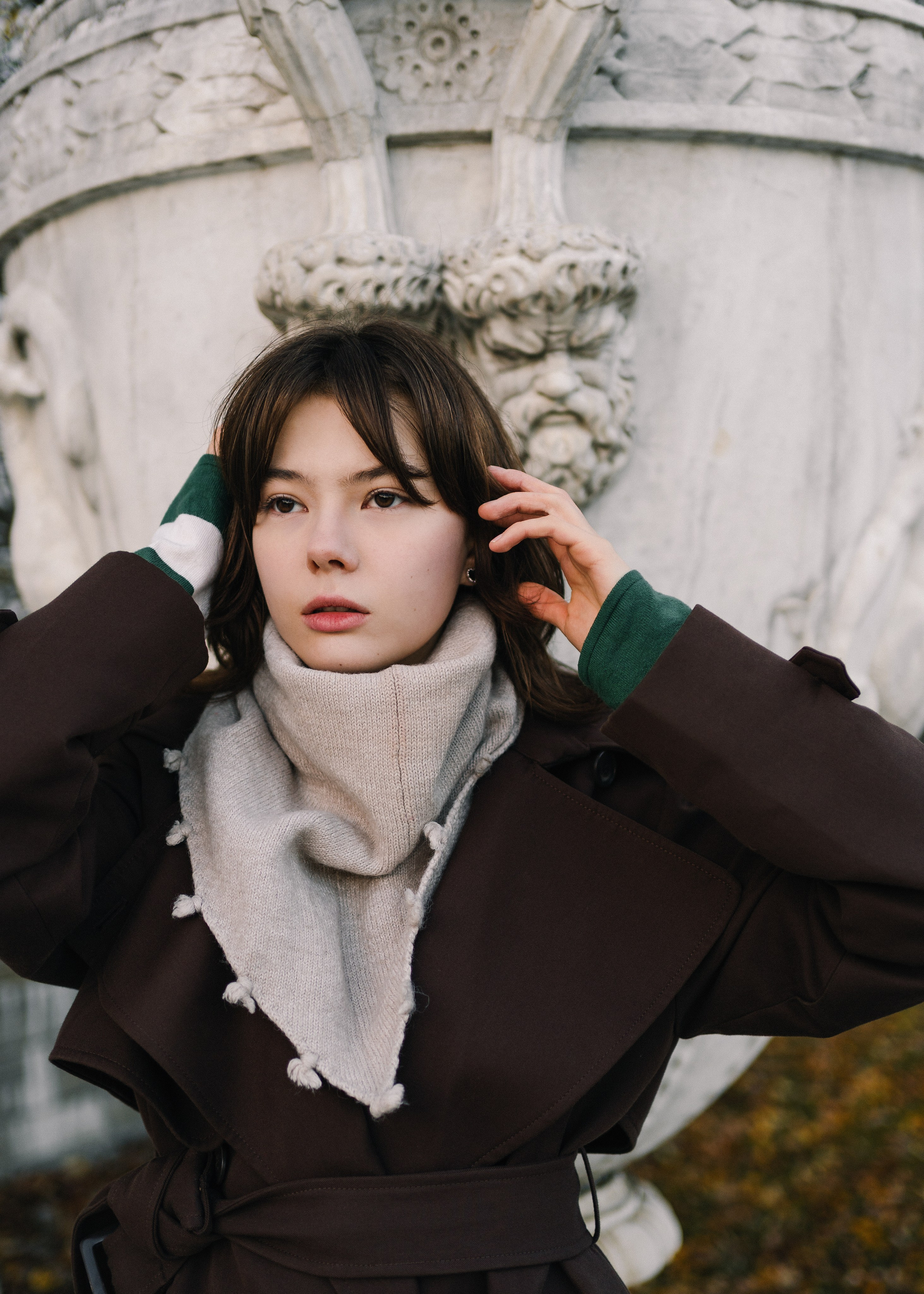 Портрет девушки с короткой стрижкой на улице на фоне скульптуры вазы