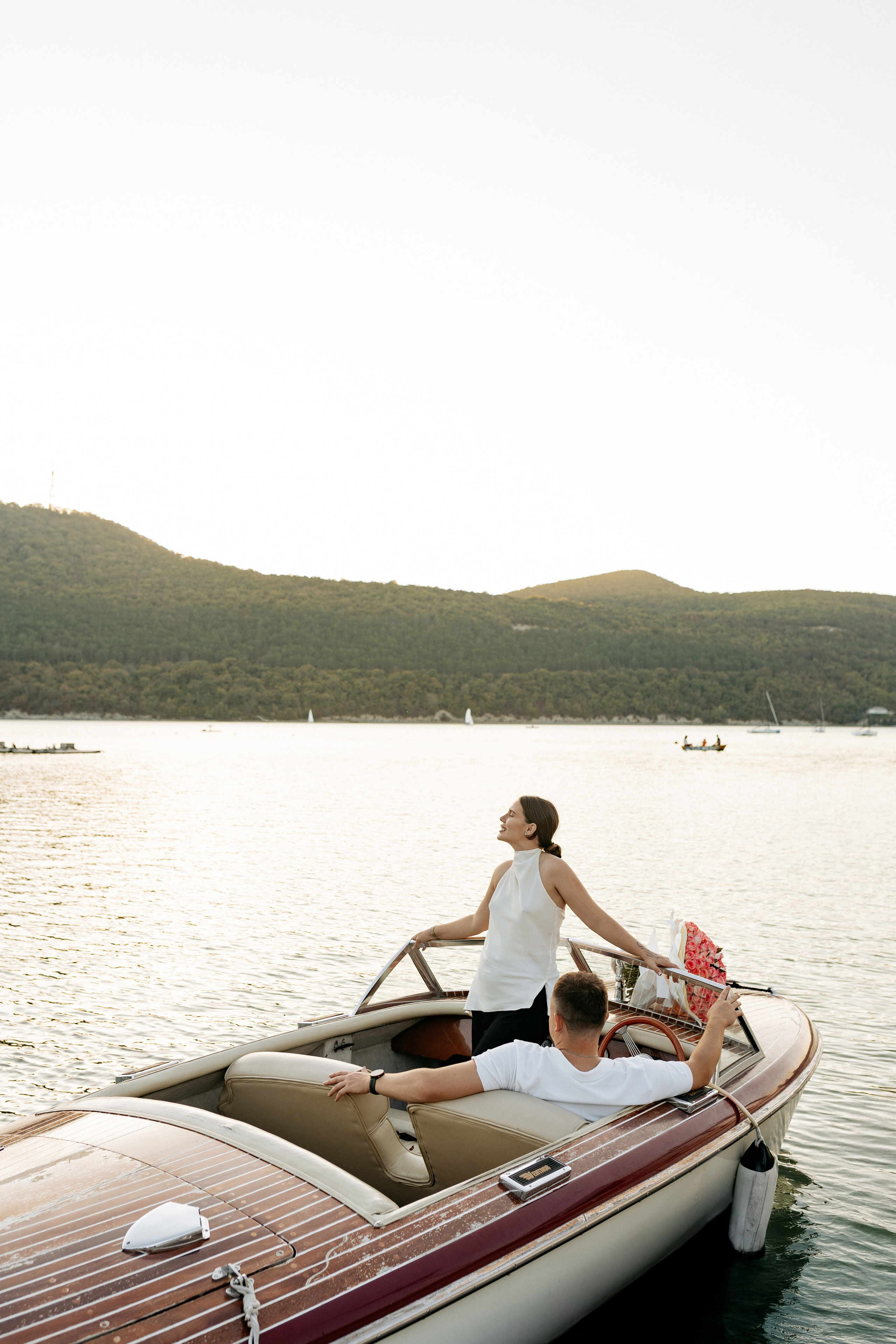Романтическая фотосессия на ретро-катере в Абрау-Дюрсо. Пара счастливо позирует фотографу на фоне бирюзовой глади озера. Невеста в красивом платье и жених в элегантном образе создают идеальную картину любви и счастья на фоне виноградных холмов.
