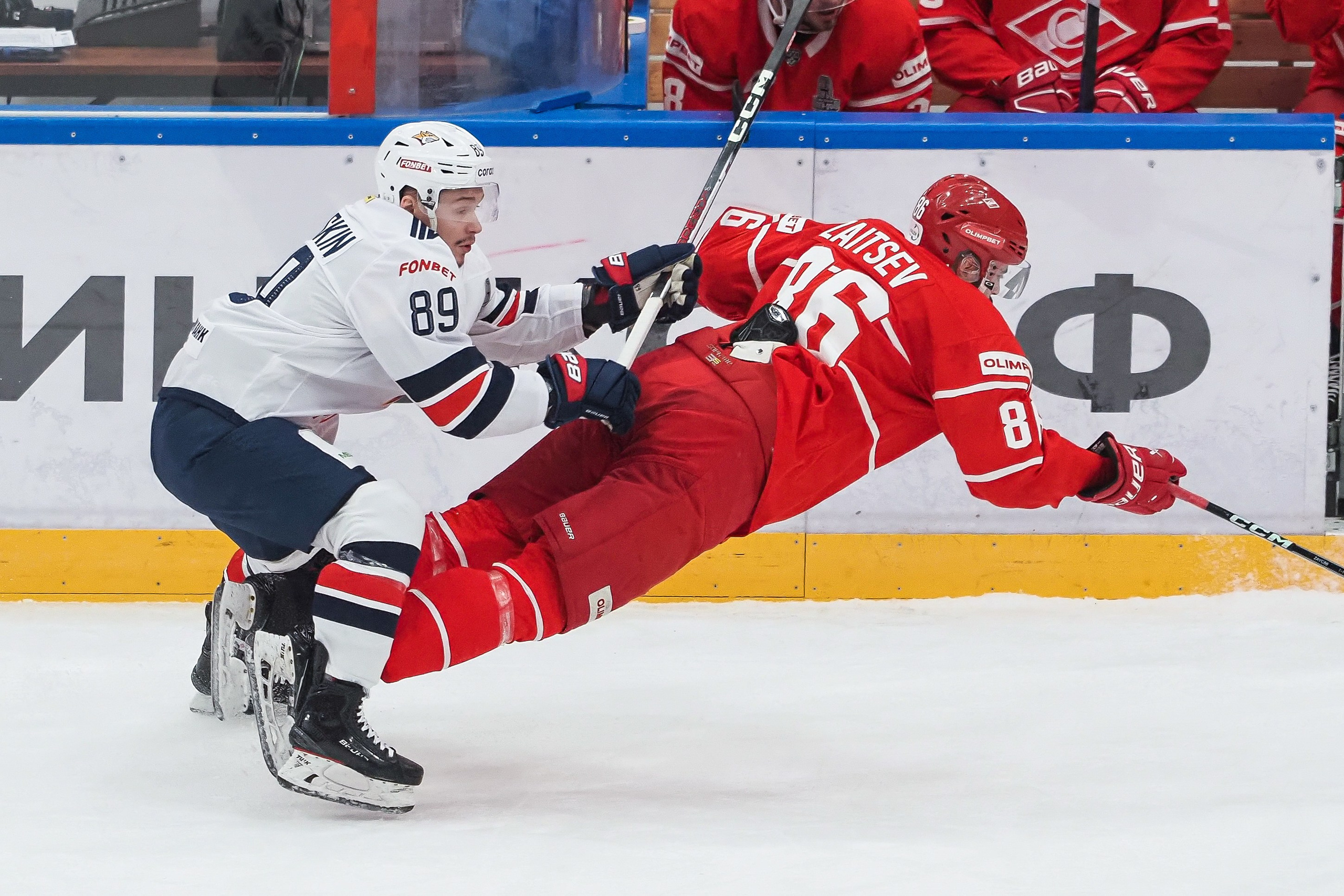 Хоккеисты активно борются за шайбу, падая у борта